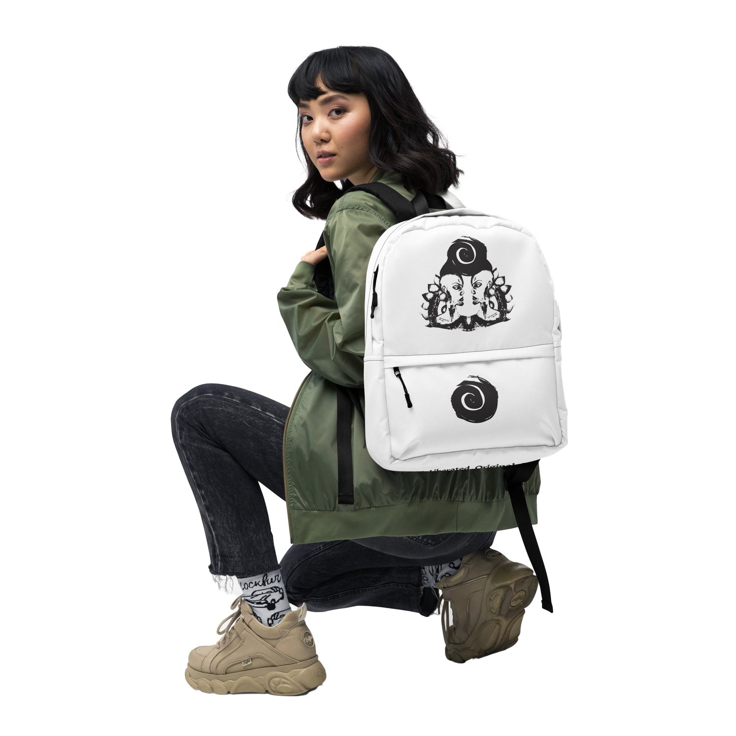 A model wearing the white backpack featuring a hand-drawn, culturally inspired design of two mirrored faces in bold black on the main panel, paired with a striking black spiral motif on the spacious front pocket, celebrating self-expression and individuality in modern bohemian style fashion by K.L.O.E.
