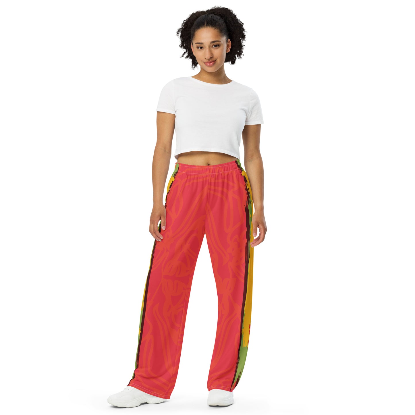 Wide-leg pants with a red base and abstract brushstroke side panels in yellow, green, and black, inspired by bold color play and cultural expression.