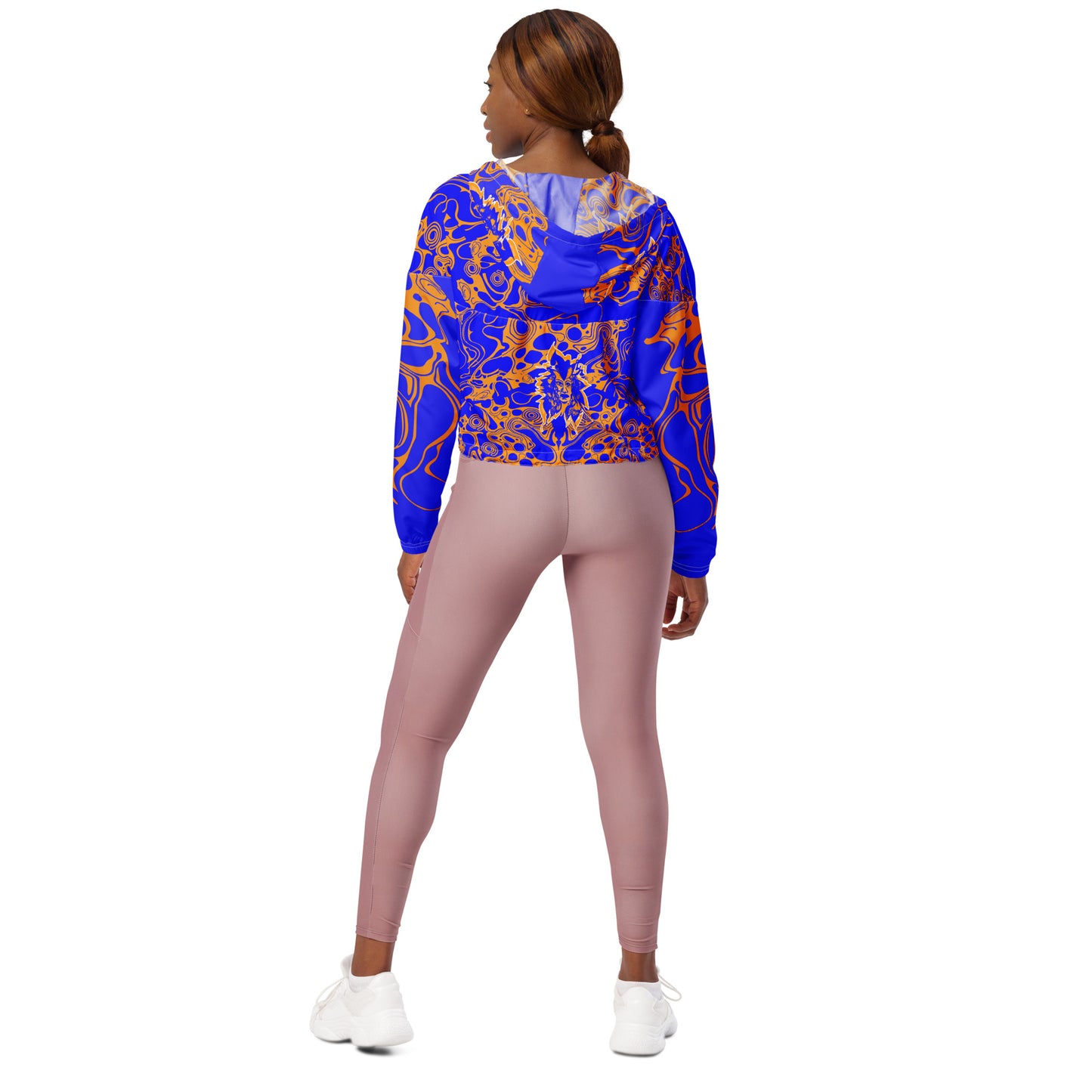 Product mockup - model wearing a vibrant blue and orange cropped windbreaker from Kloe Store featuring abstract swirl pattern, a front zipper, drawstring hood, and elastic cuffs, offering a stylish and modern streetwear look.