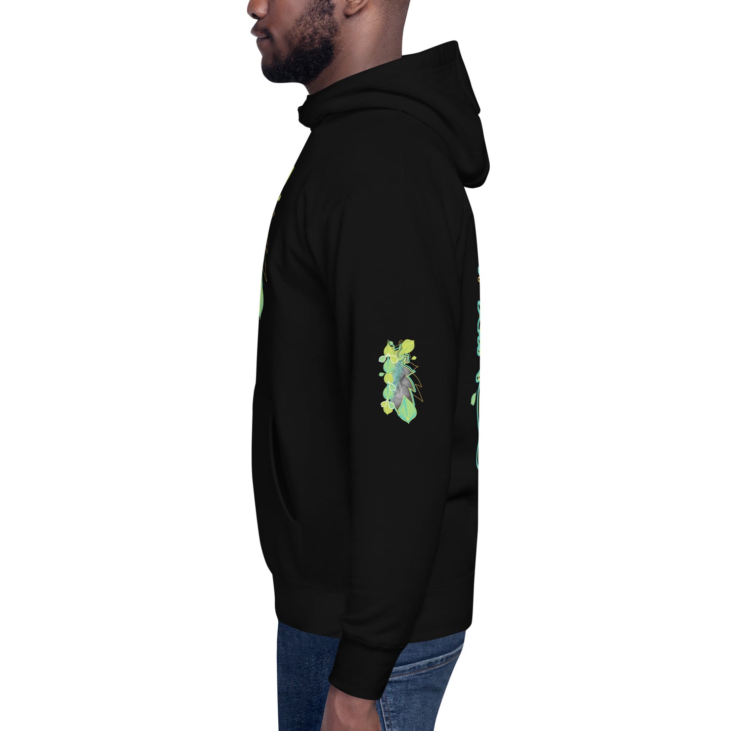 Side view of black K.L.O.E. hoodie with vibrant green and yellow leaf patterns framing a detailed hand-drawn face design. A modern bohemian style statement that celebrates individuality, artistic expression, and culturally inspired fashion, on a model.