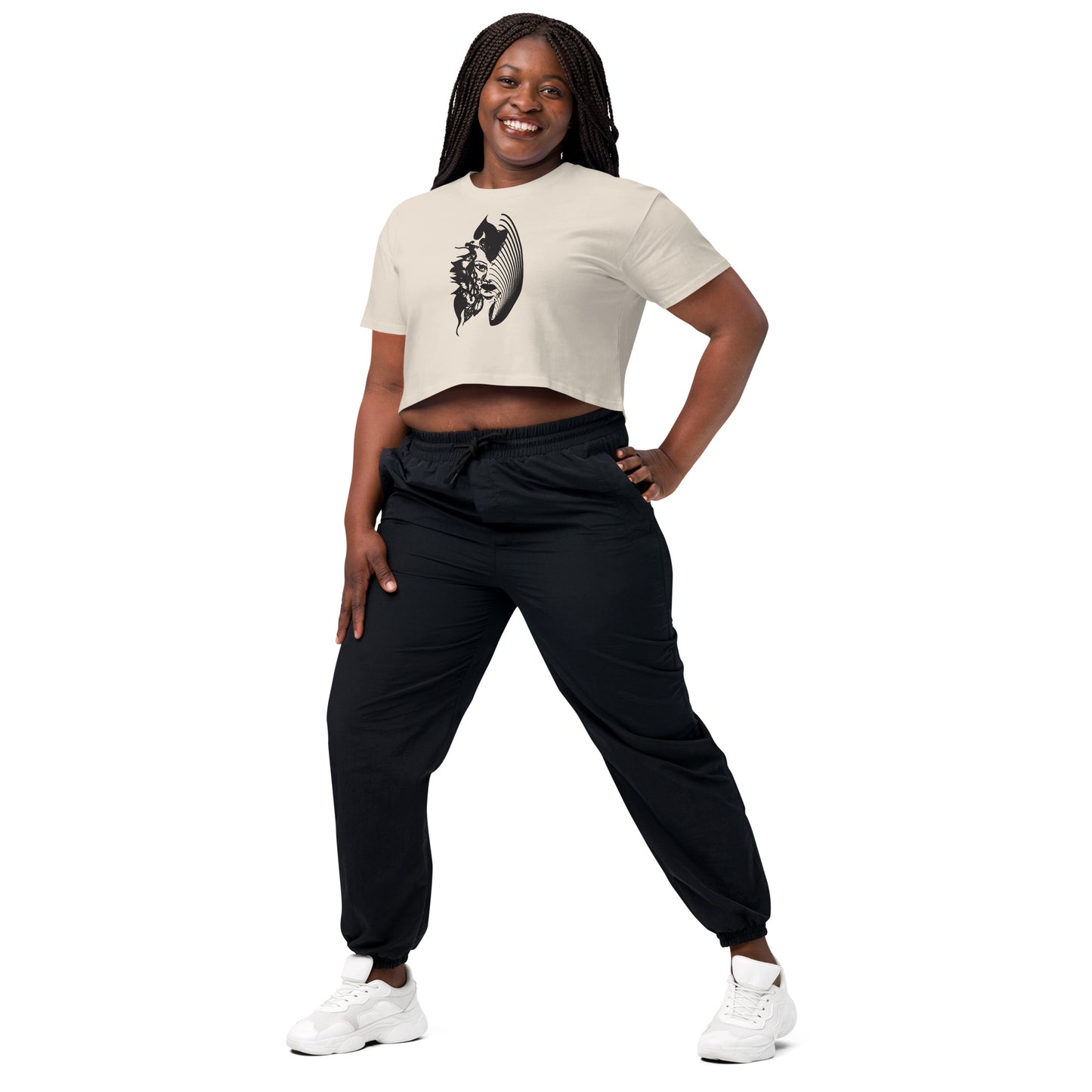 A model wearing a bone K.L.O.E. crop t-shirt featuring a culturally inspired, hand-drawn black graphic of a bold, expressive face surrounded by intricate details, celebrating individuality and artistic self-expression in modern bohemian style fashion.