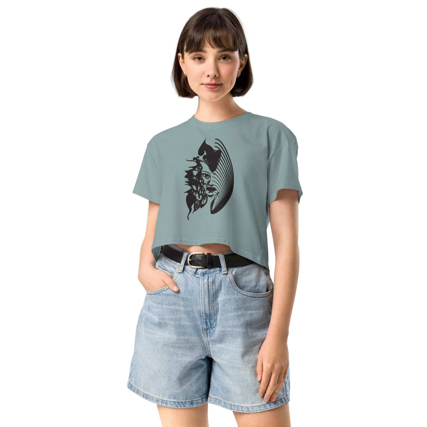 A model wearing a mineral K.L.O.E. crop t-shirt featuring a culturally inspired, hand-drawn black graphic of a bold, expressive face surrounded by intricate details, celebrating individuality and artistic self-expression in modern bohemian style fashion.