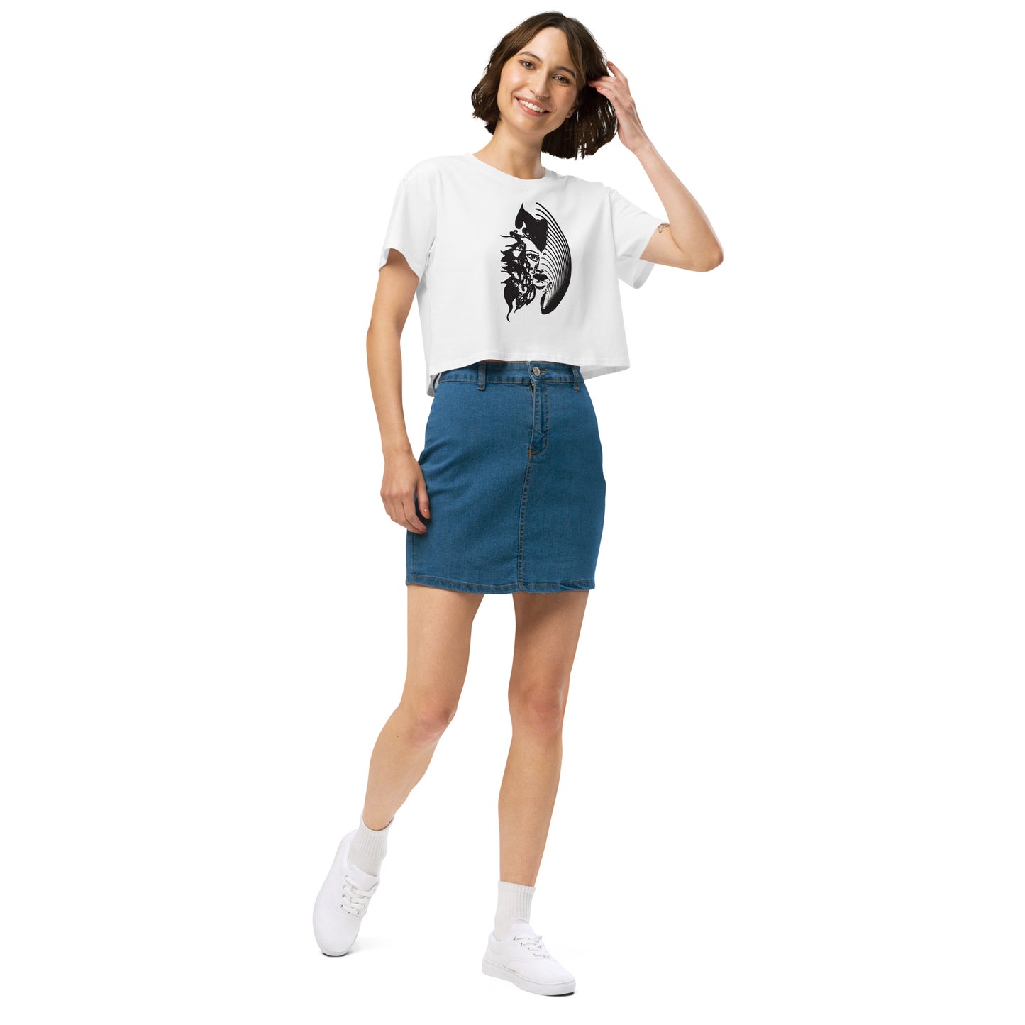 A model wearing white K.L.O.E. crop t-shirt featuring a culturally inspired, hand-drawn black graphic of a bold, expressive face surrounded by intricate details, celebrating individuality and artistic self-expression in modern bohemian style fashion.
