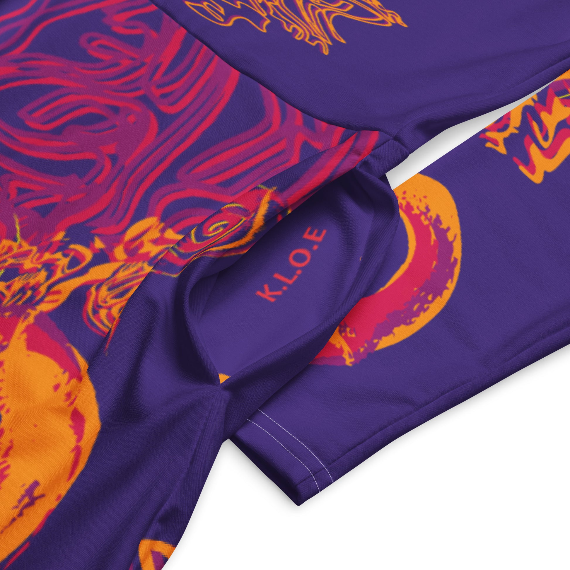 Bold purple long sleeve dress with vibrant orange and red culturally inspired patterns, featuring mirrored face design and swirling motifs — expressive fashion from KLOE’s The Secret Chambers of I & I collection, on a model, showing pockets details.