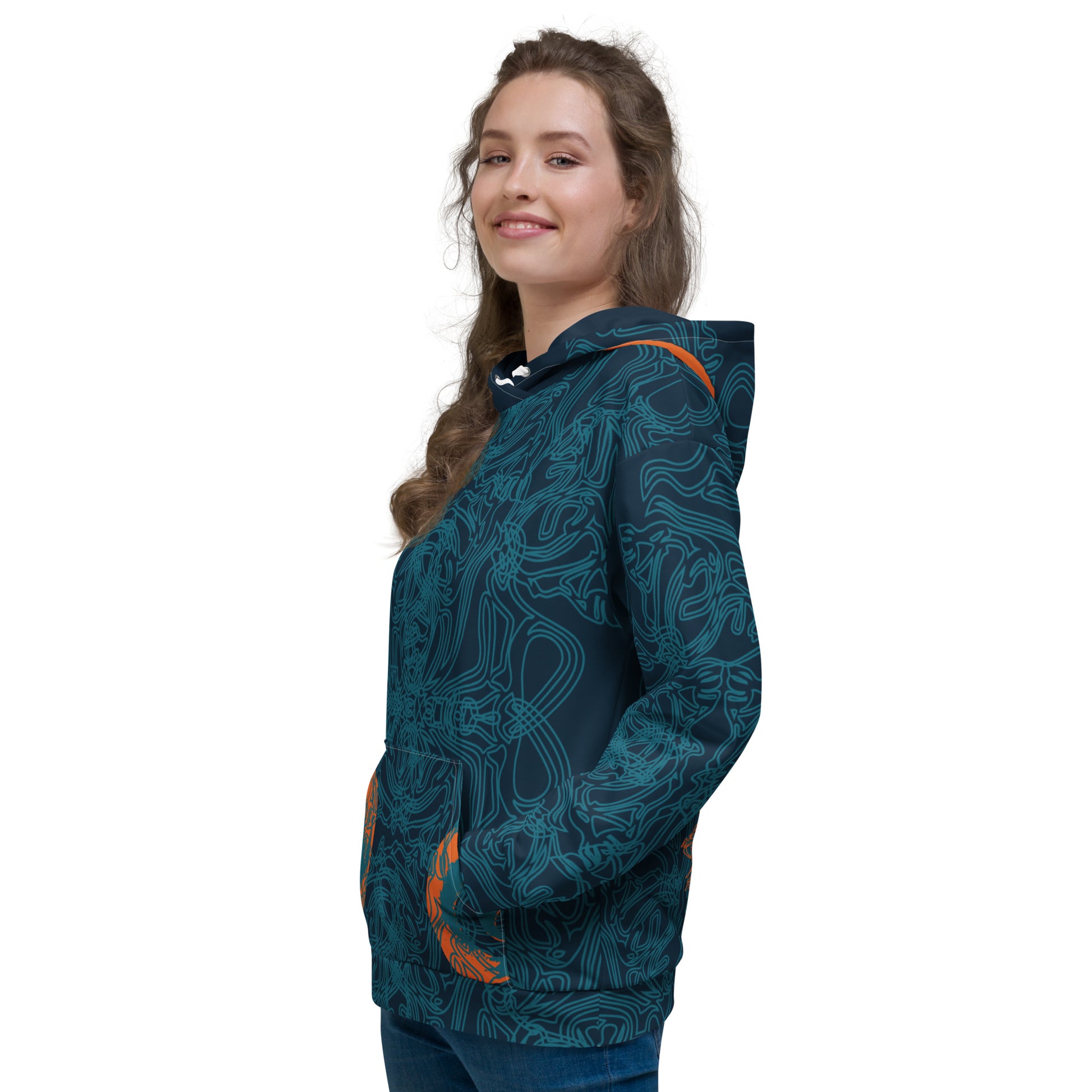 Side front view of a navy blue hoodie with intricate cyan linework, subtle orange tribal accents on the pockets, and a spacious hood, on a model.