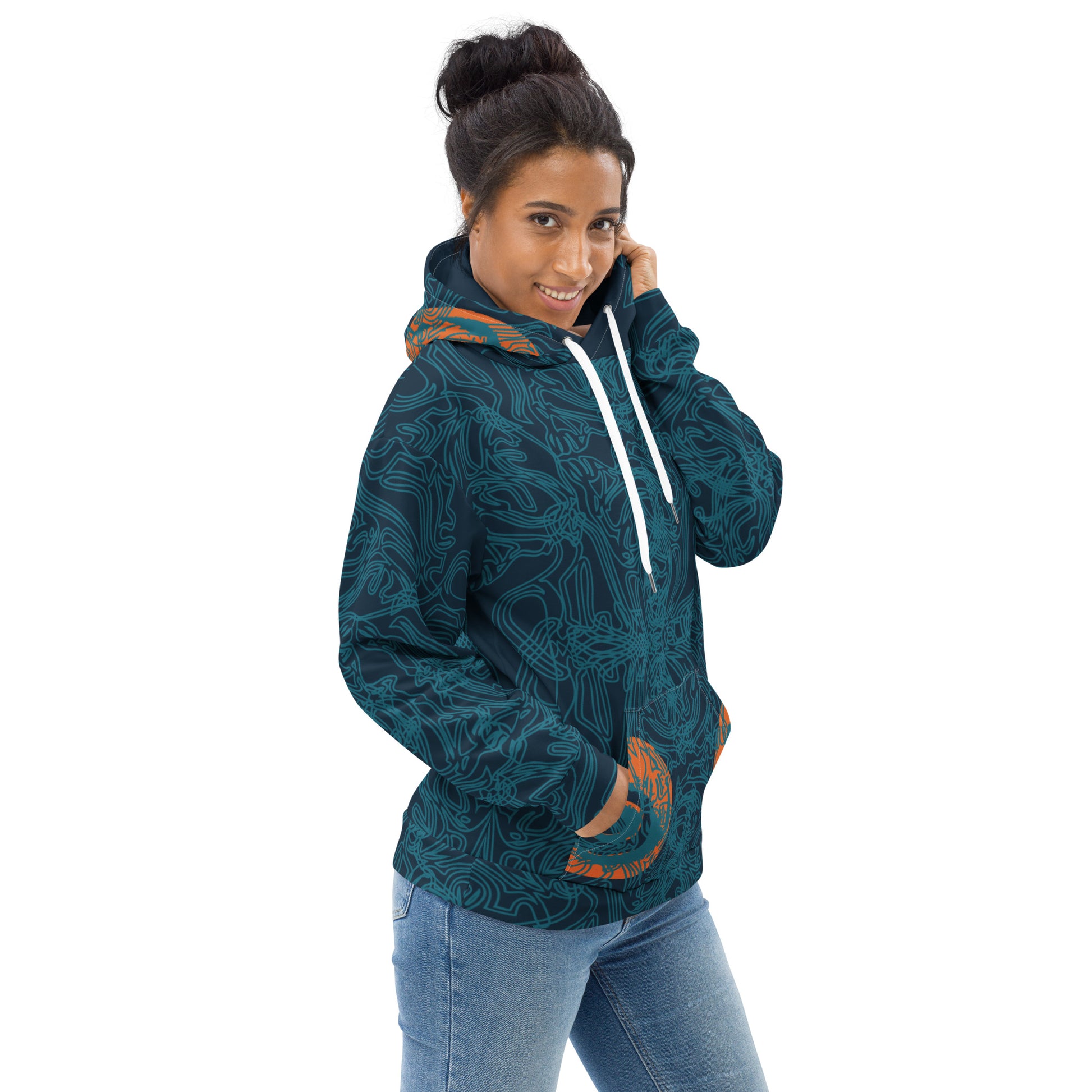 Side front view of a navy blue hoodie with intricate cyan linework, subtle orange tribal accents on the pockets, and a spacious hood, on a model.
