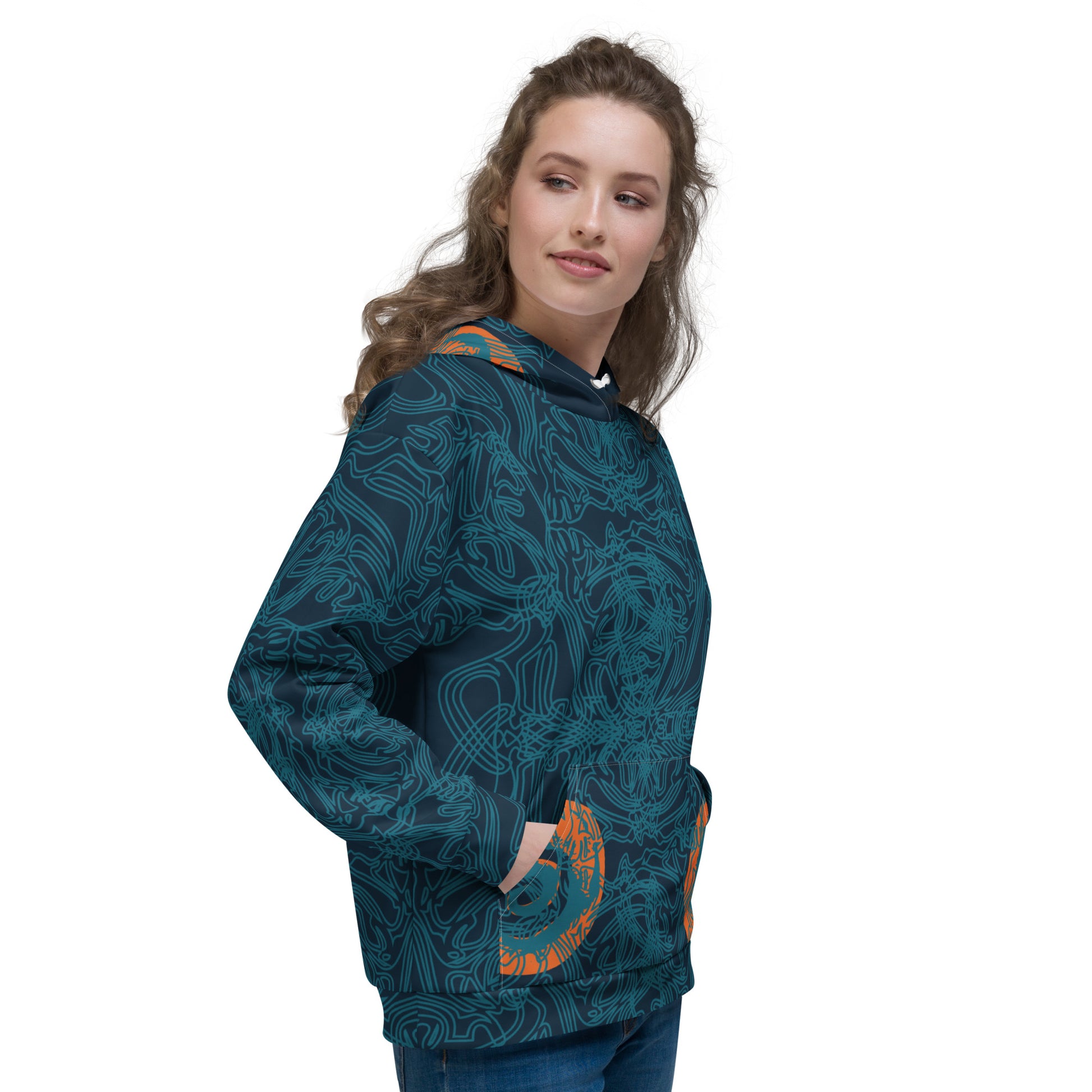 Side front view of a navy blue hoodie with intricate cyan linework, subtle orange tribal accents on the pockets, and a spacious hood, on a model.