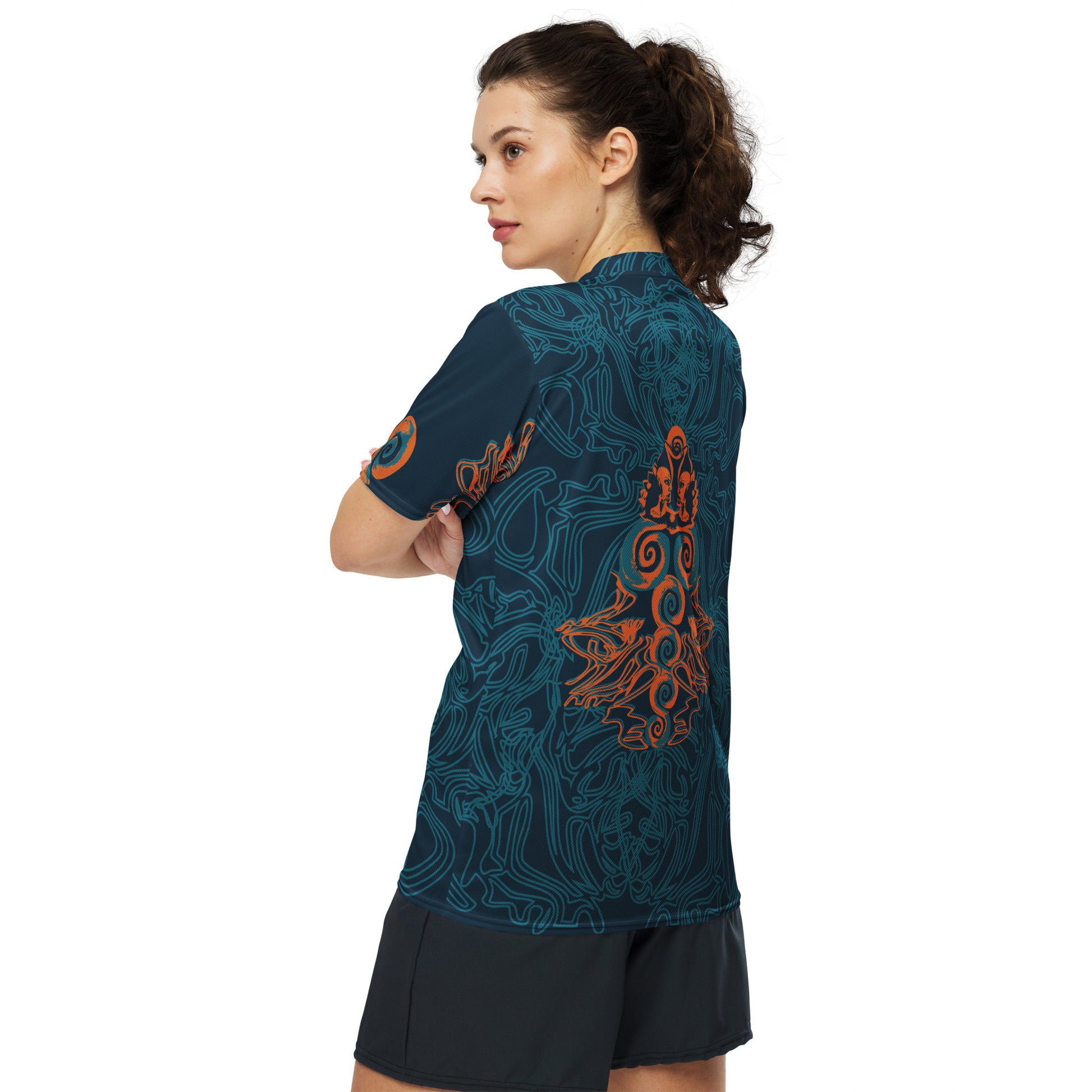 Side view of a navy blue sports jersey showcasing swirling cyan patterns and a striking orange tribal-inspired emblem, blending cultural artistry with modern streetwear, on a model.