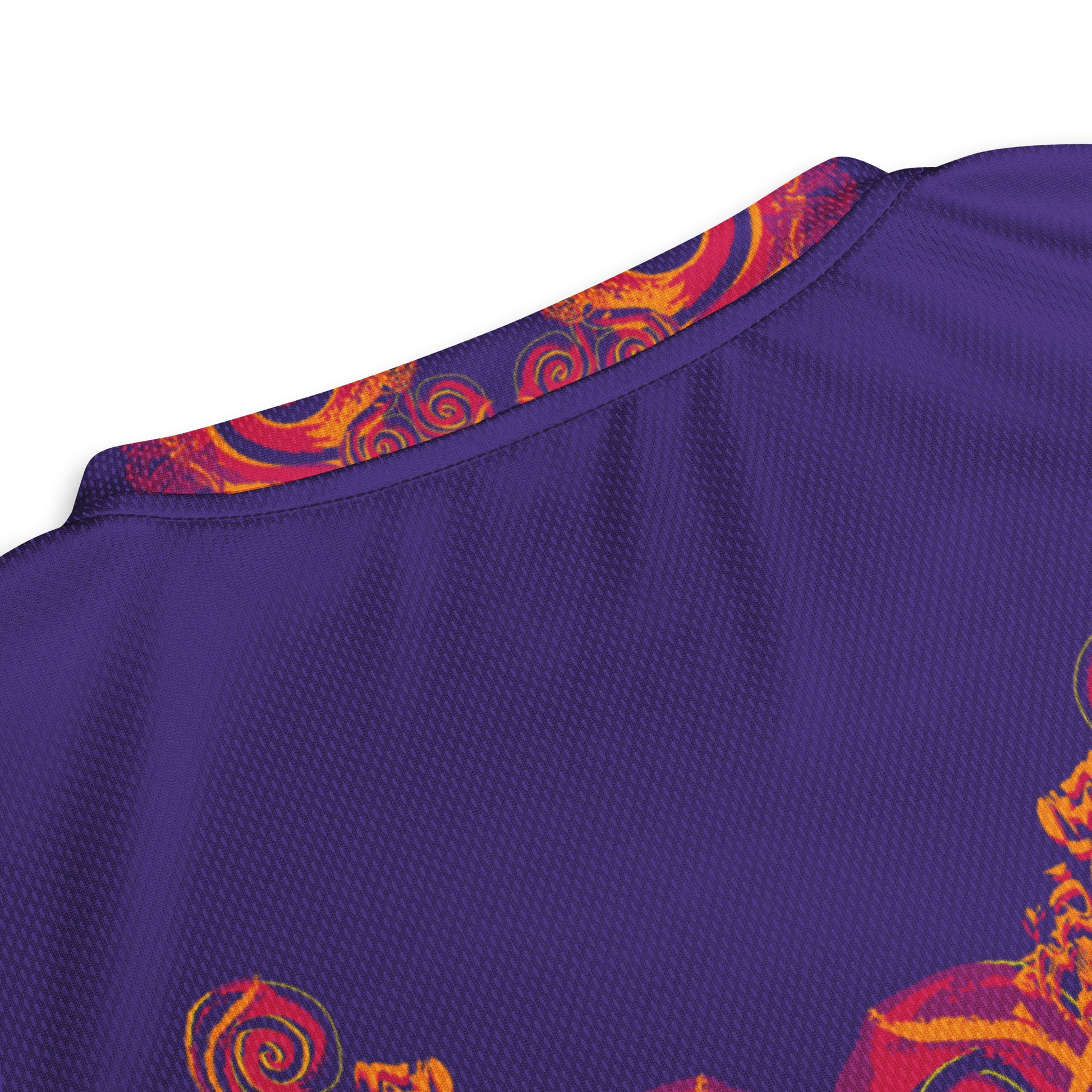 Detail view of  a neck line of a vibrant purple sports jersey with bold orange and red culturally inspired patterns, featuring mirrored faces and swirling designs – expressive fashion from KLOE’s The Secret Chambers of I & I collection.