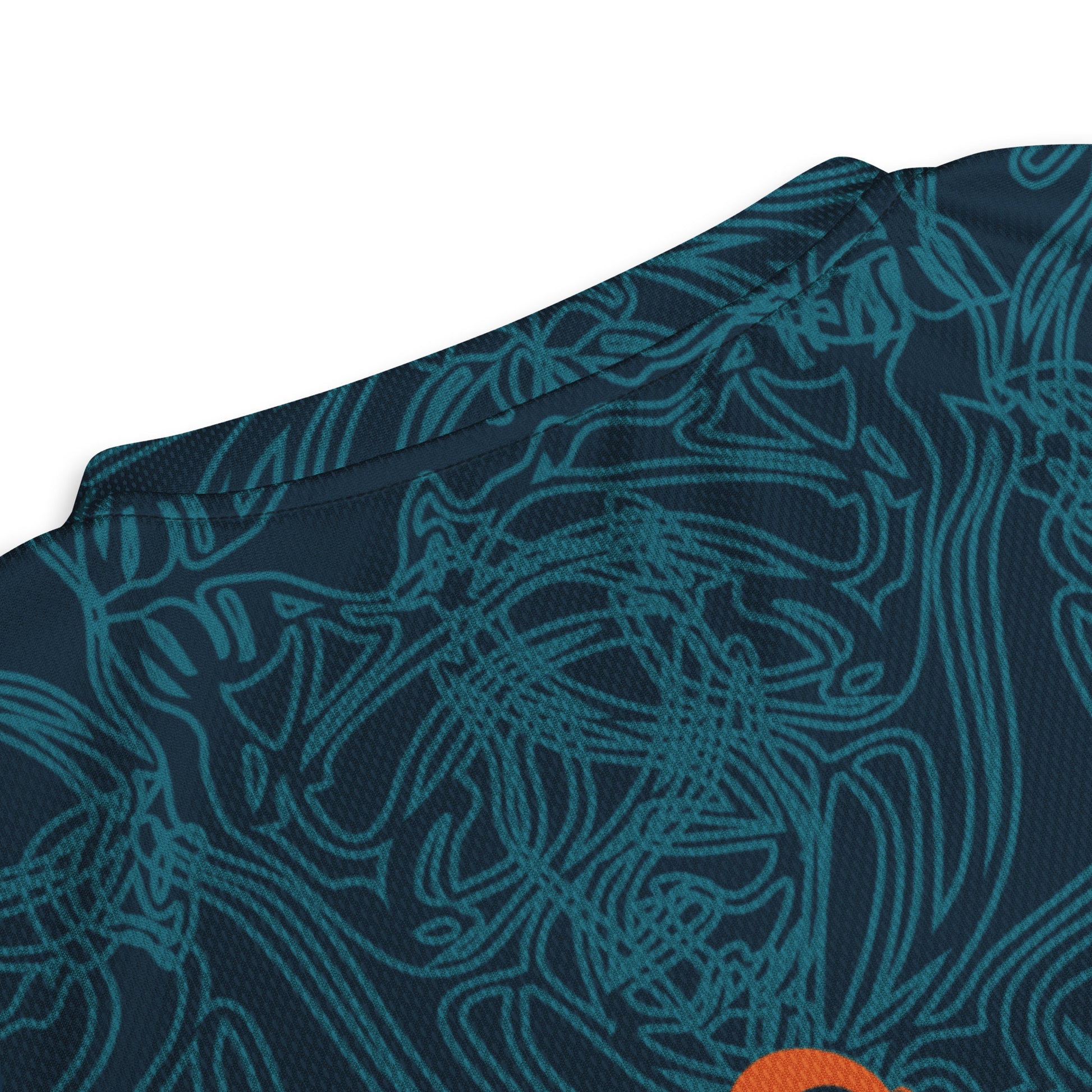 Neck view of a navy blue sports jersey showcasing swirling cyan patterns and a striking orange tribal-inspired emblem, blending cultural artistry with modern streetwear.