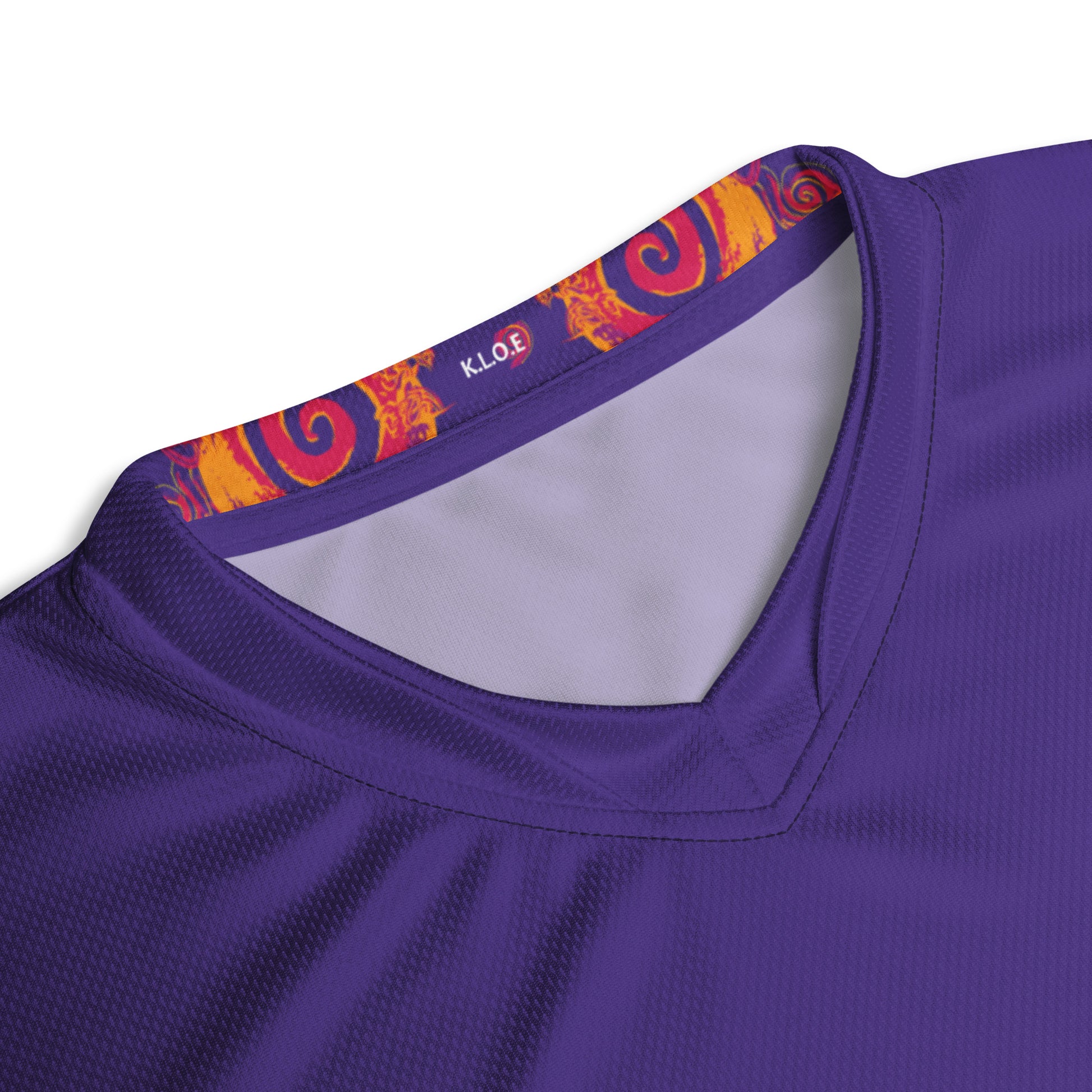 Detail view of the neck line of the vibrant purple sports jersey with bold orange and red culturally inspired patterns, featuring mirrored faces and swirling designs – expressive fashion from KLOE’s The Secret Chambers of I & I collection.