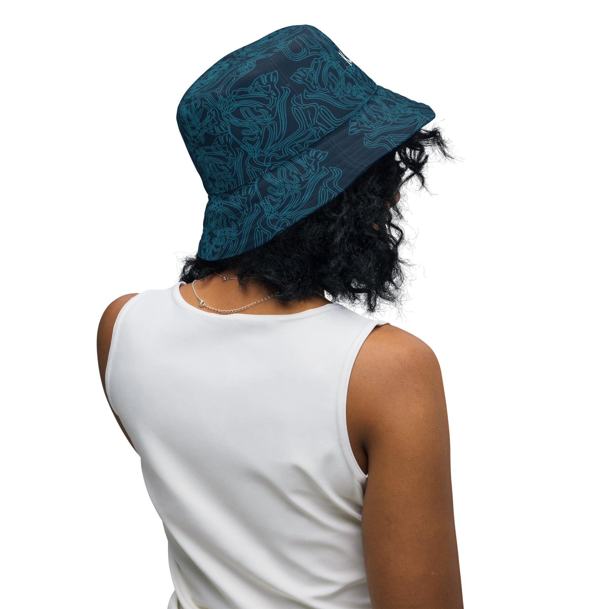 Reversible bucket hat with a navy blue base and intricate cyan linework, featuring an abstract, artistic pattern, worn by a model.