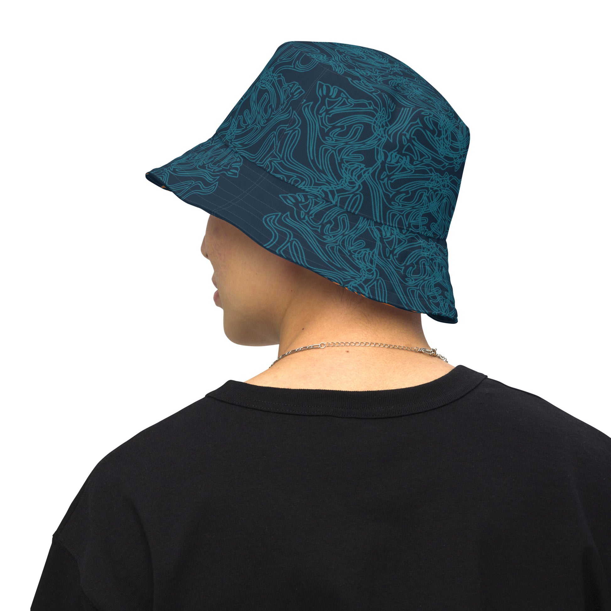 Reversible bucket hat with a navy blue base and intricate cyan linework, featuring an abstract, artistic pattern, worn by a model.
