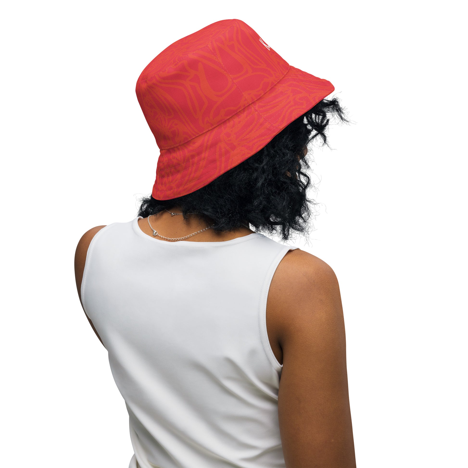 Reversible red-orange bucket hat with cultural swirl design and mirrored face motif on one side, and K.L.O.E wordmark on the other.