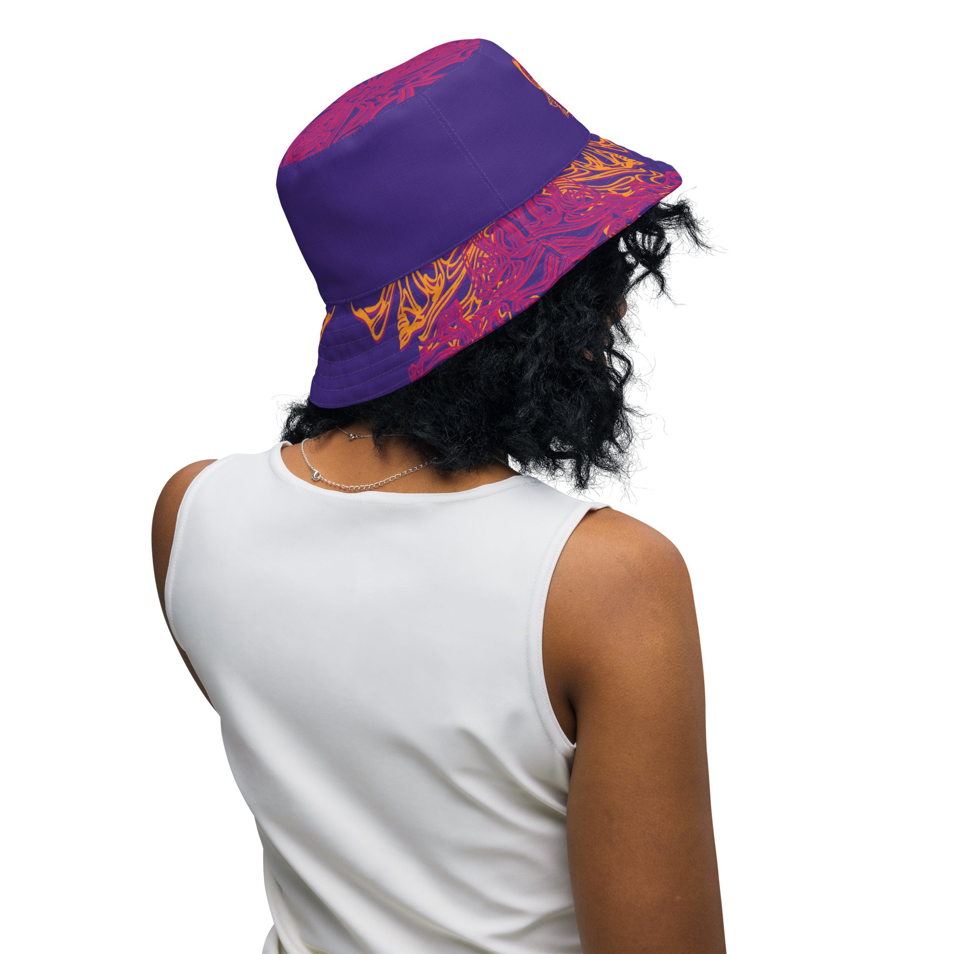 Reversible purple bucket hat with bold orange and red culturally inspired patterns, featuring abstract swirls and mirrored face design — artistic fashion accessory from KLOE’s The Secret Chambers of I & I collection, on a model.