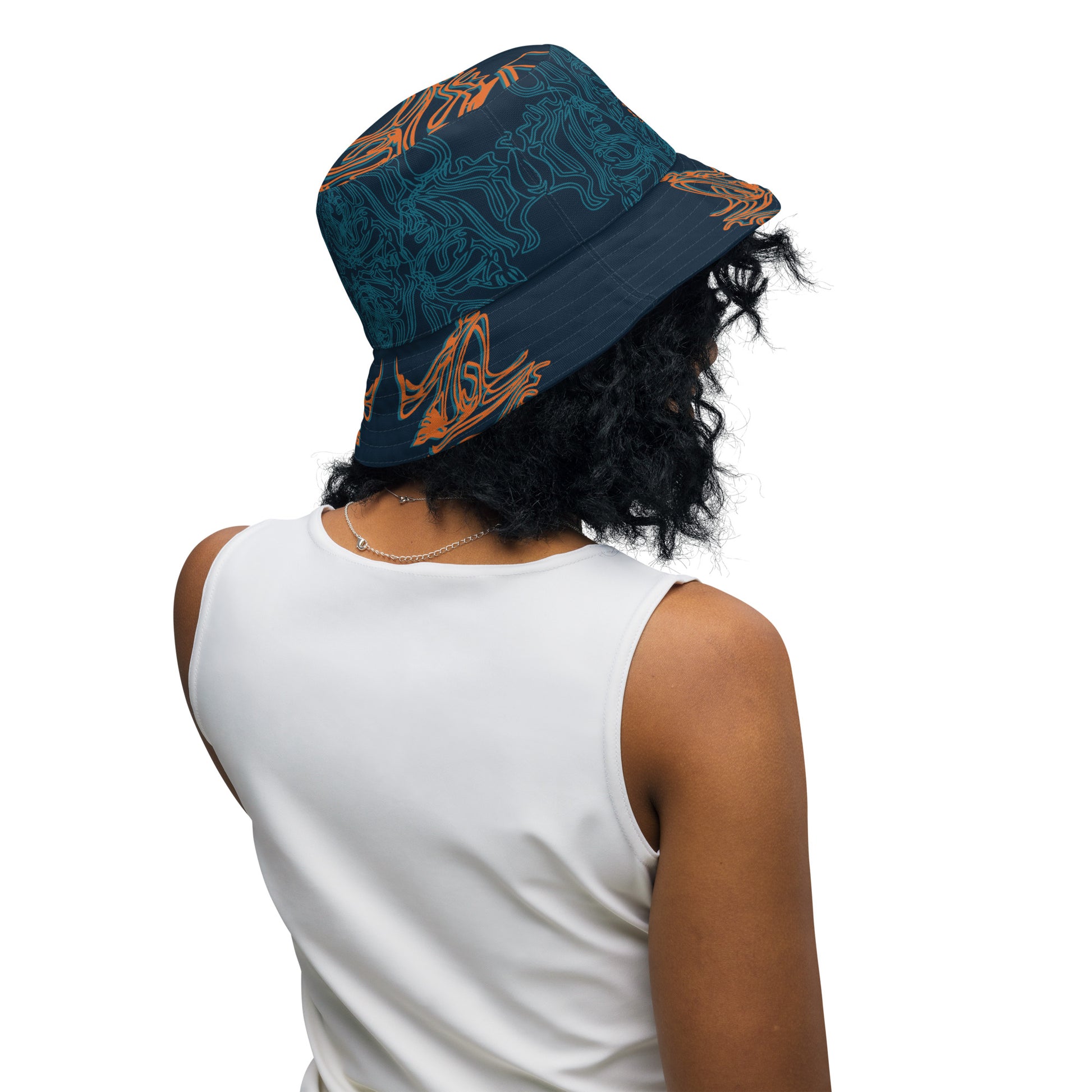 Reversible bucket hat featuring a small orange mirrored face motif and bold tribal-inspired patterns, blending art and streetwear.
