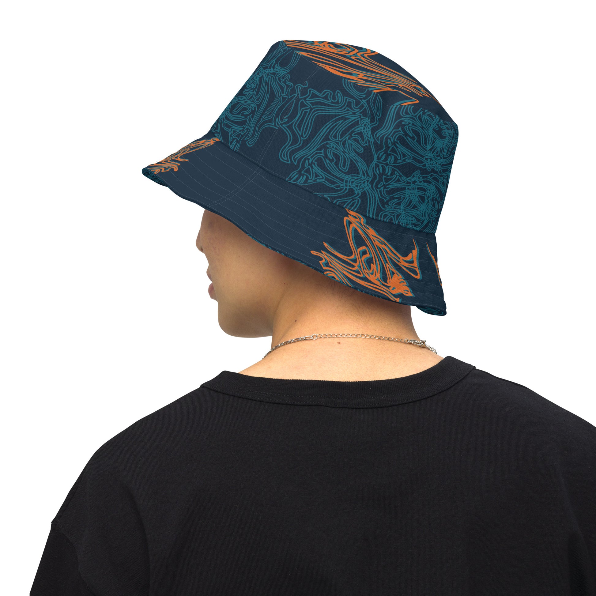 Reversible bucket hat featuring a small orange mirrored face motif and bold tribal-inspired patterns, blending art and streetwear.