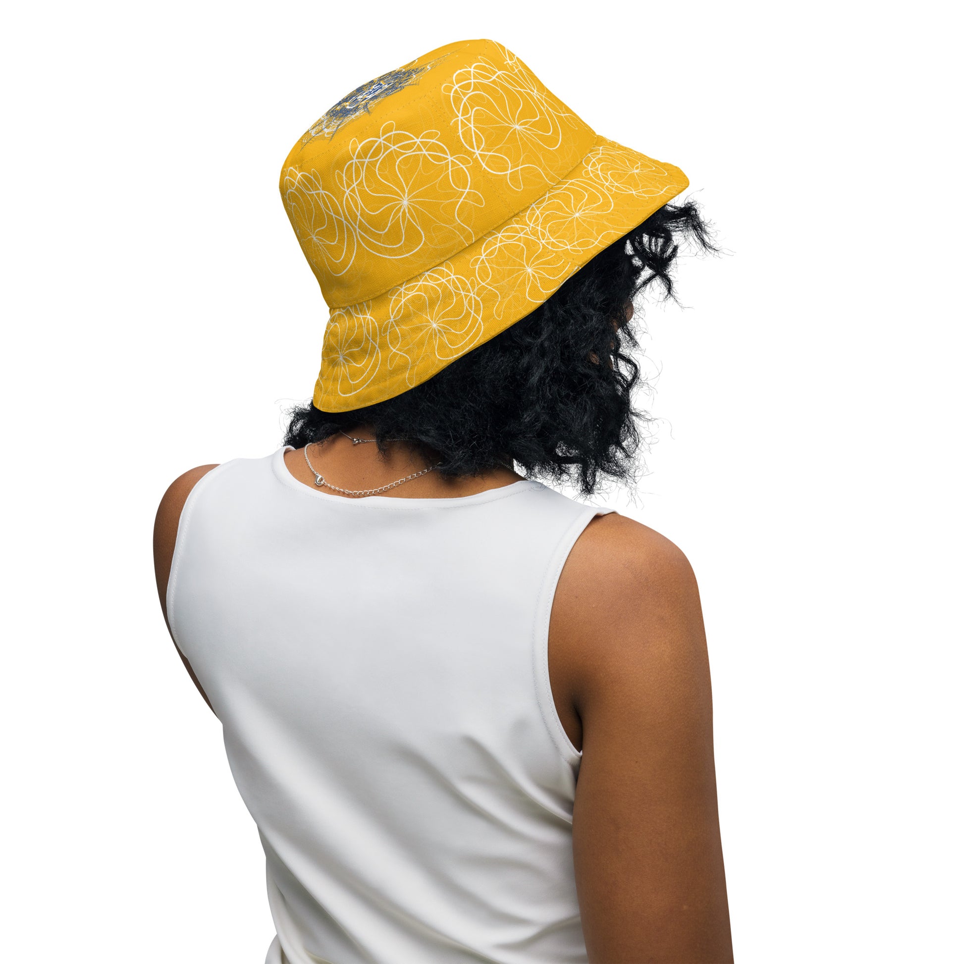 Reversible bucket hat featuring navy and golden yellow sides with abstract white linework and mirrored face emblems, blending hand-drawn cultural art with bold, expressive streetwear style.