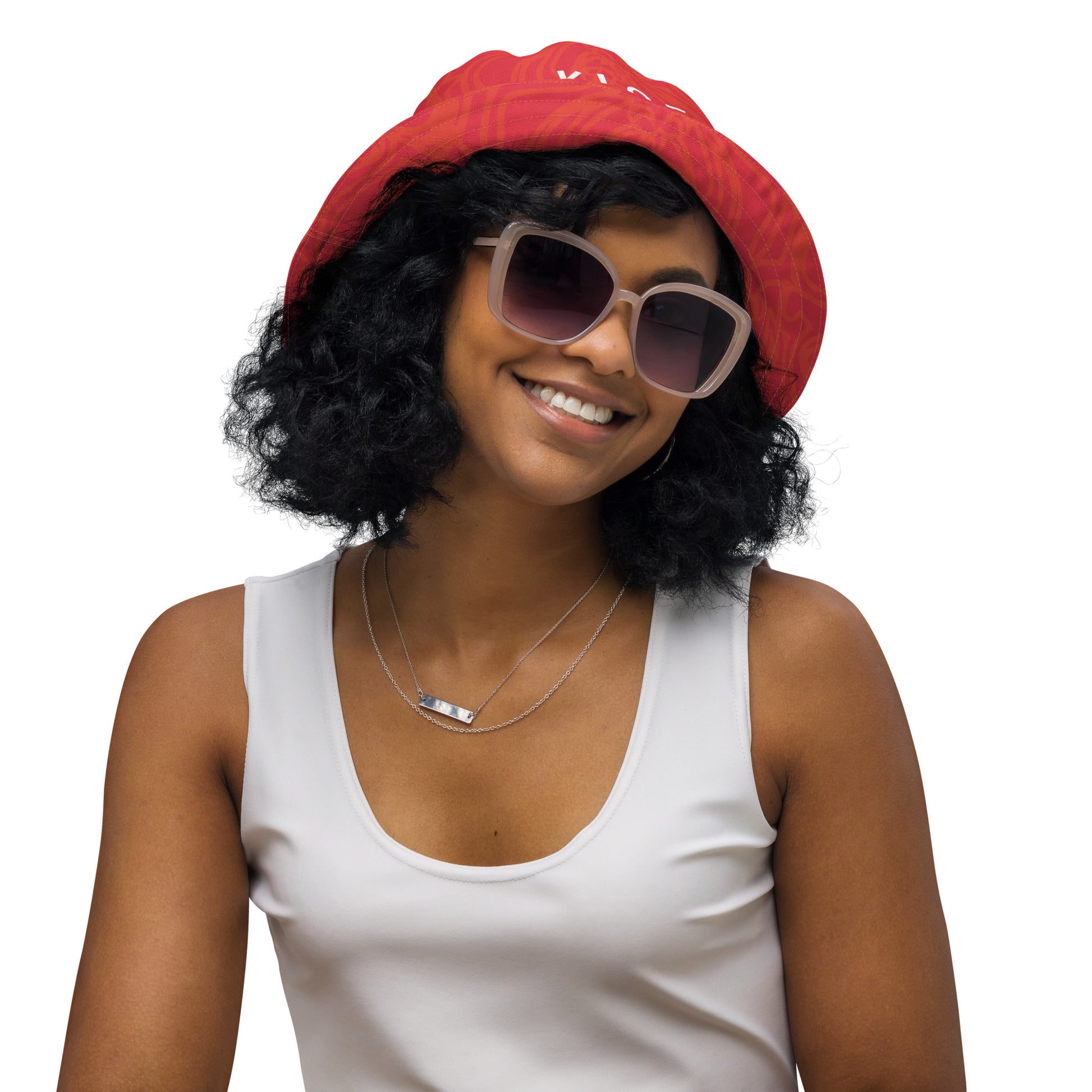 Reversible red-orange bucket hat with cultural swirl design and mirrored face motif on one side, and K.L.O.E wordmark on the other.