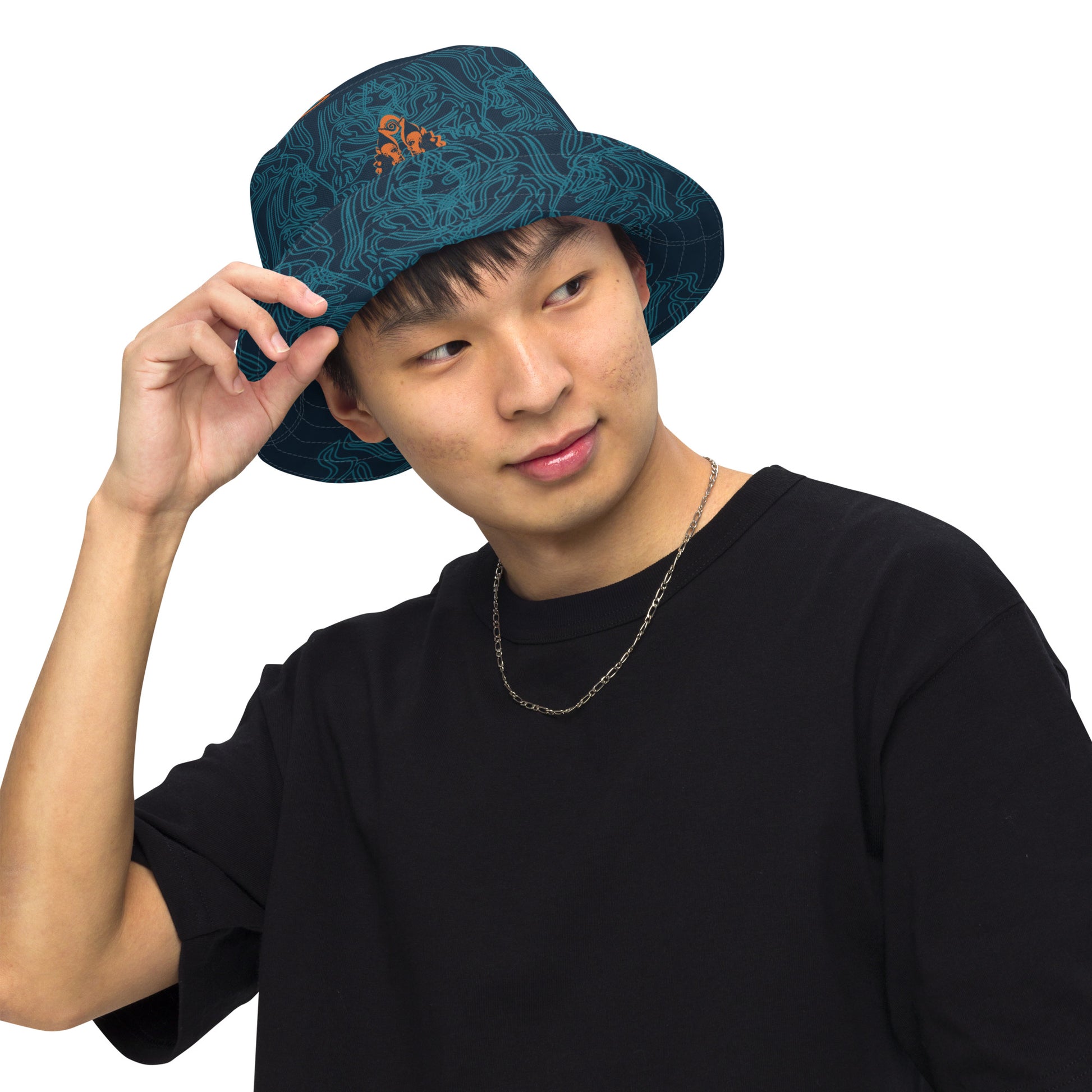 Reversible bucket hat featuring a small orange mirrored face motif and bold tribal-inspired patterns, blending art and streetwear.
