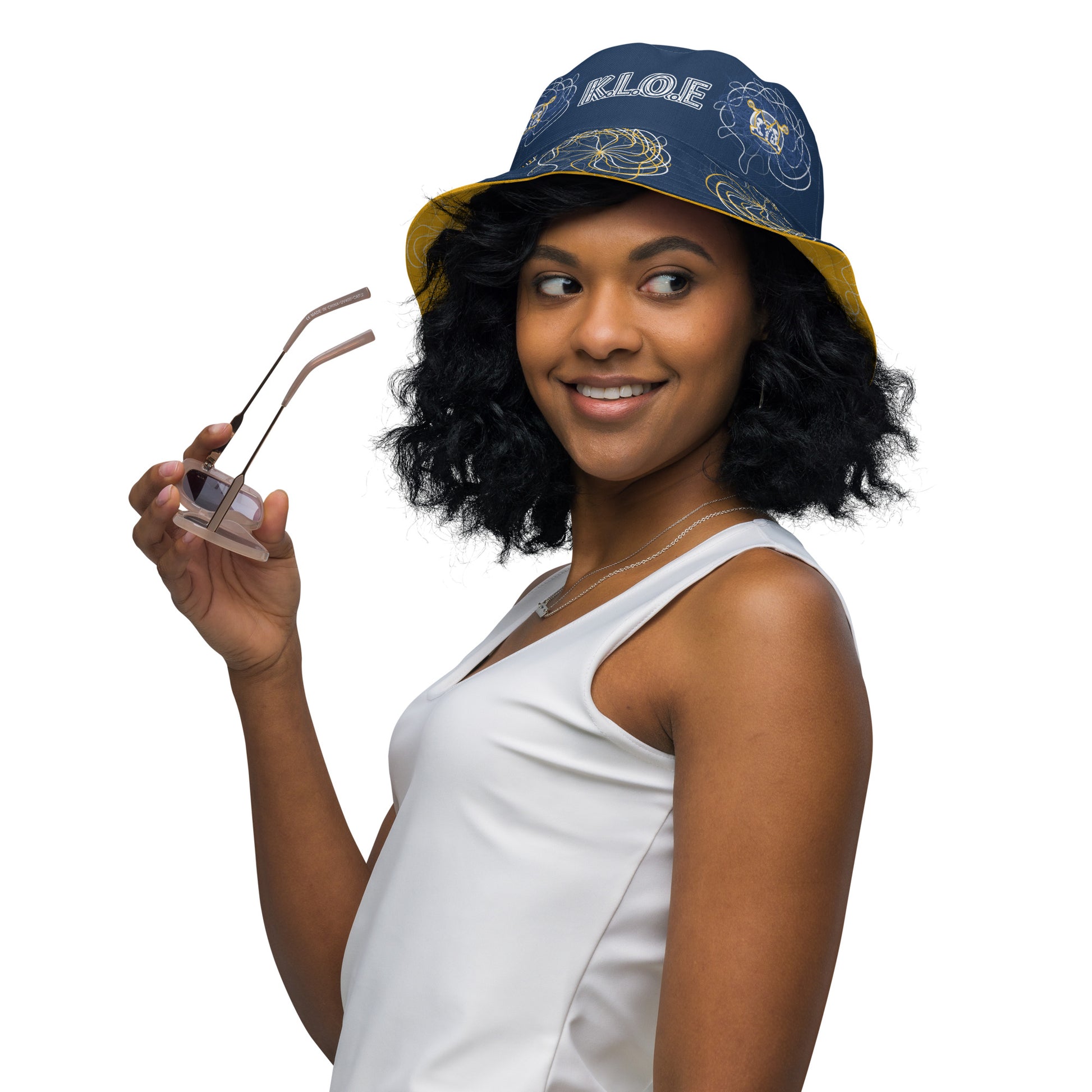 Reversible bucket hat featuring navy and golden yellow sides with abstract white linework and mirrored face emblems, blending hand-drawn cultural art with bold, expressive streetwear style.