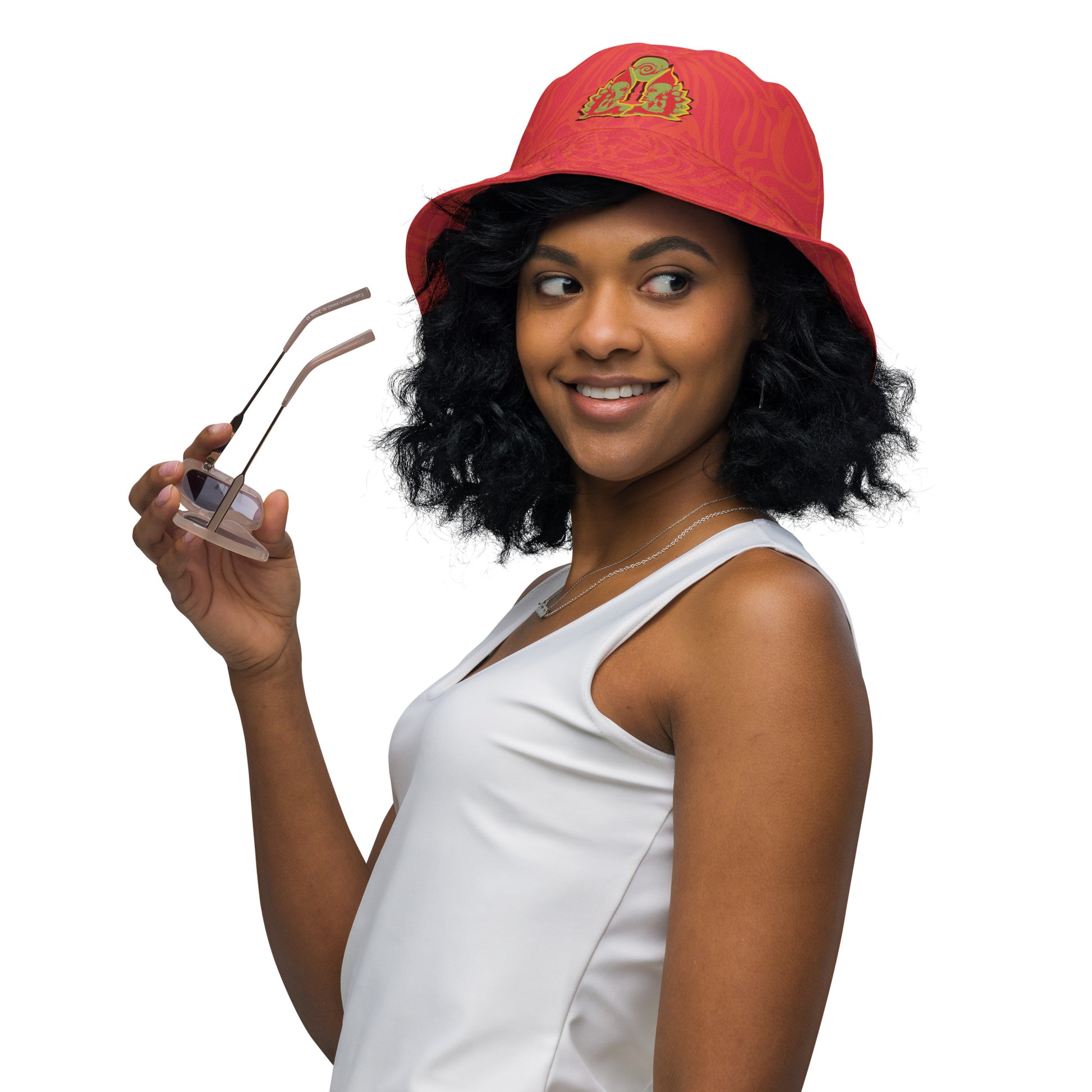 Reversible red-orange bucket hat with cultural swirl design and mirrored face motif on one side, and K.L.O.E wordmark on the other.