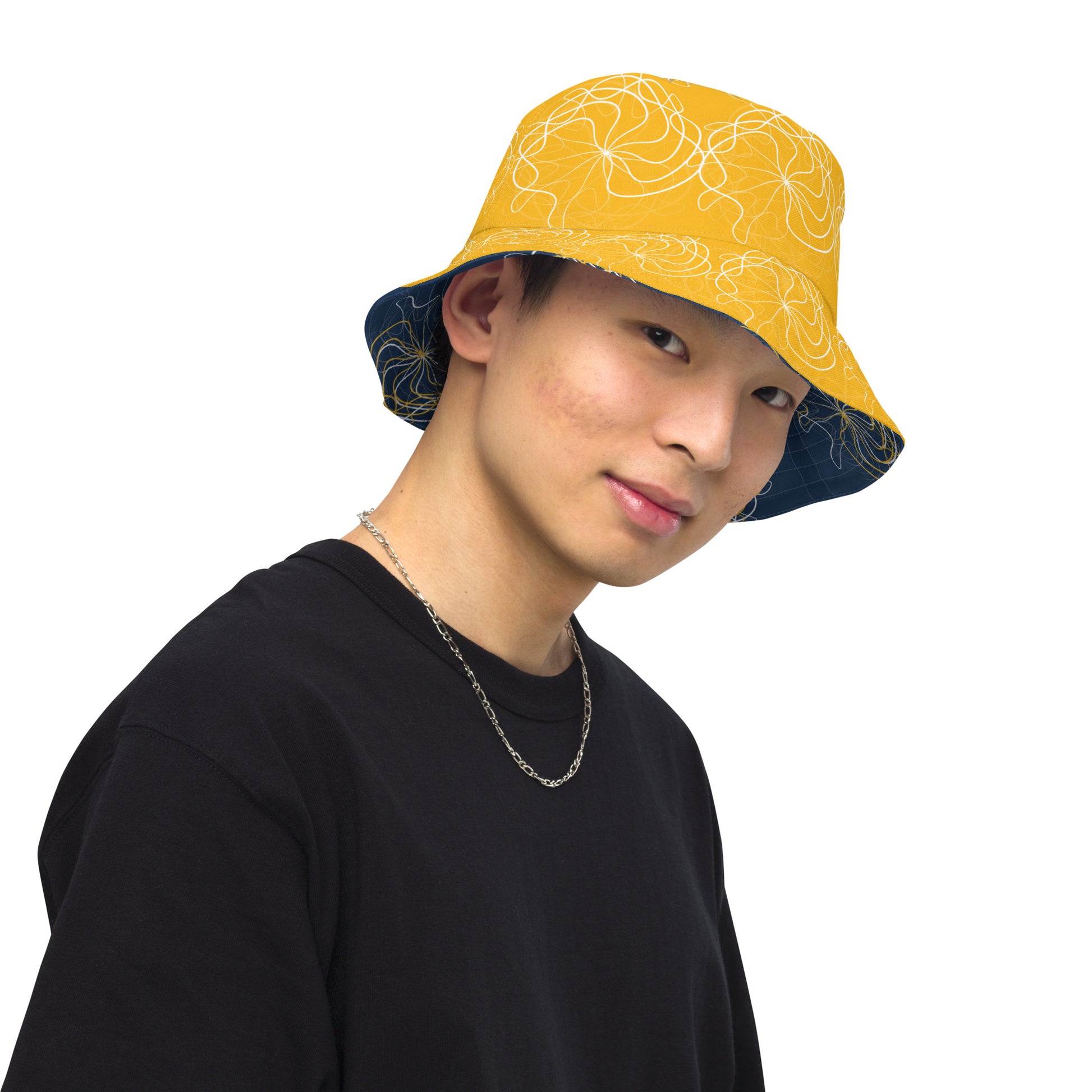 Reversible bucket hat featuring navy and golden yellow sides with abstract white linework and mirrored face emblems, blending hand-drawn cultural art with bold, expressive streetwear style.