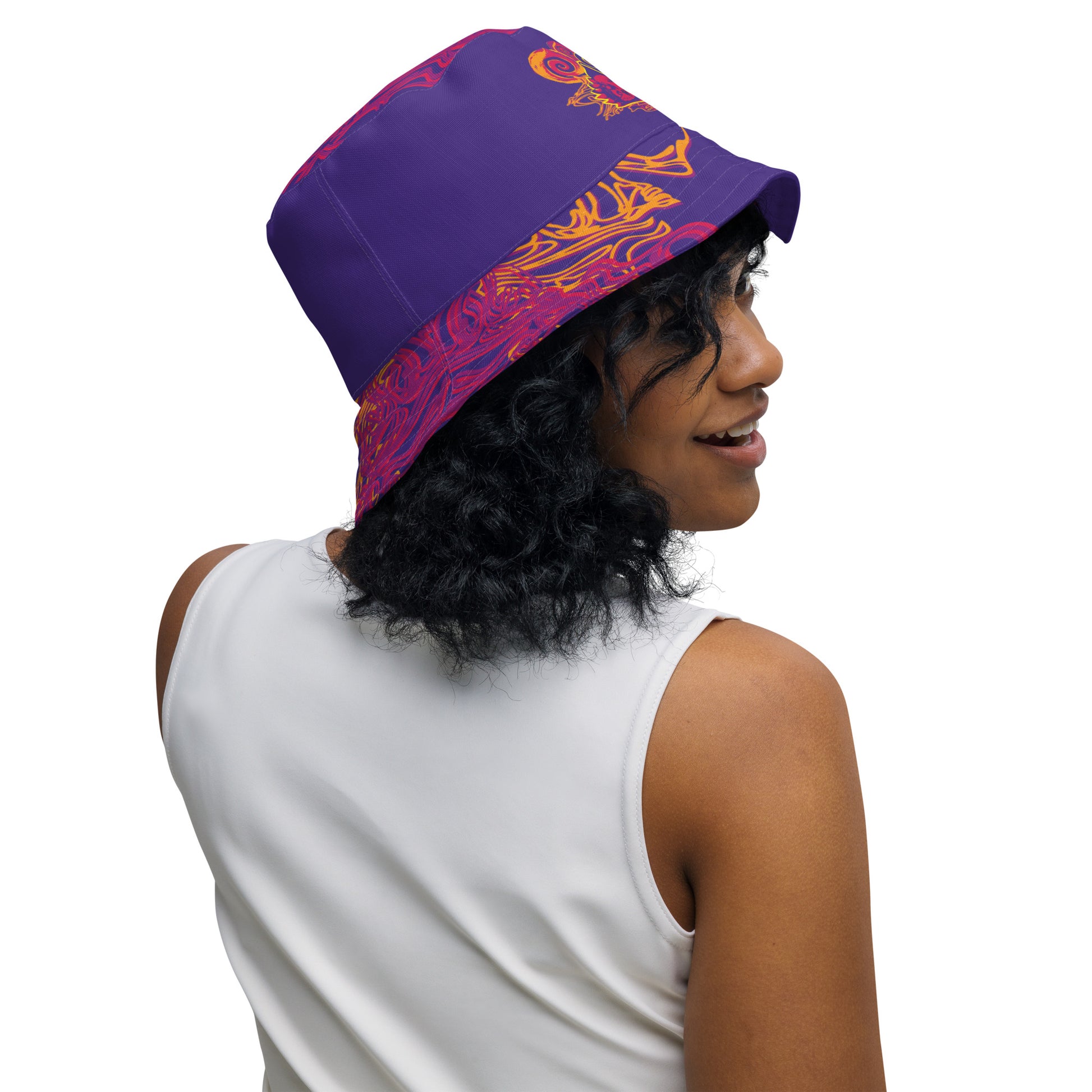 Reversible purple bucket hat with bold orange and red culturally inspired patterns, featuring abstract swirls and mirrored face design — artistic fashion accessory from KLOE’s The Secret Chambers of I & I collection, on a model.