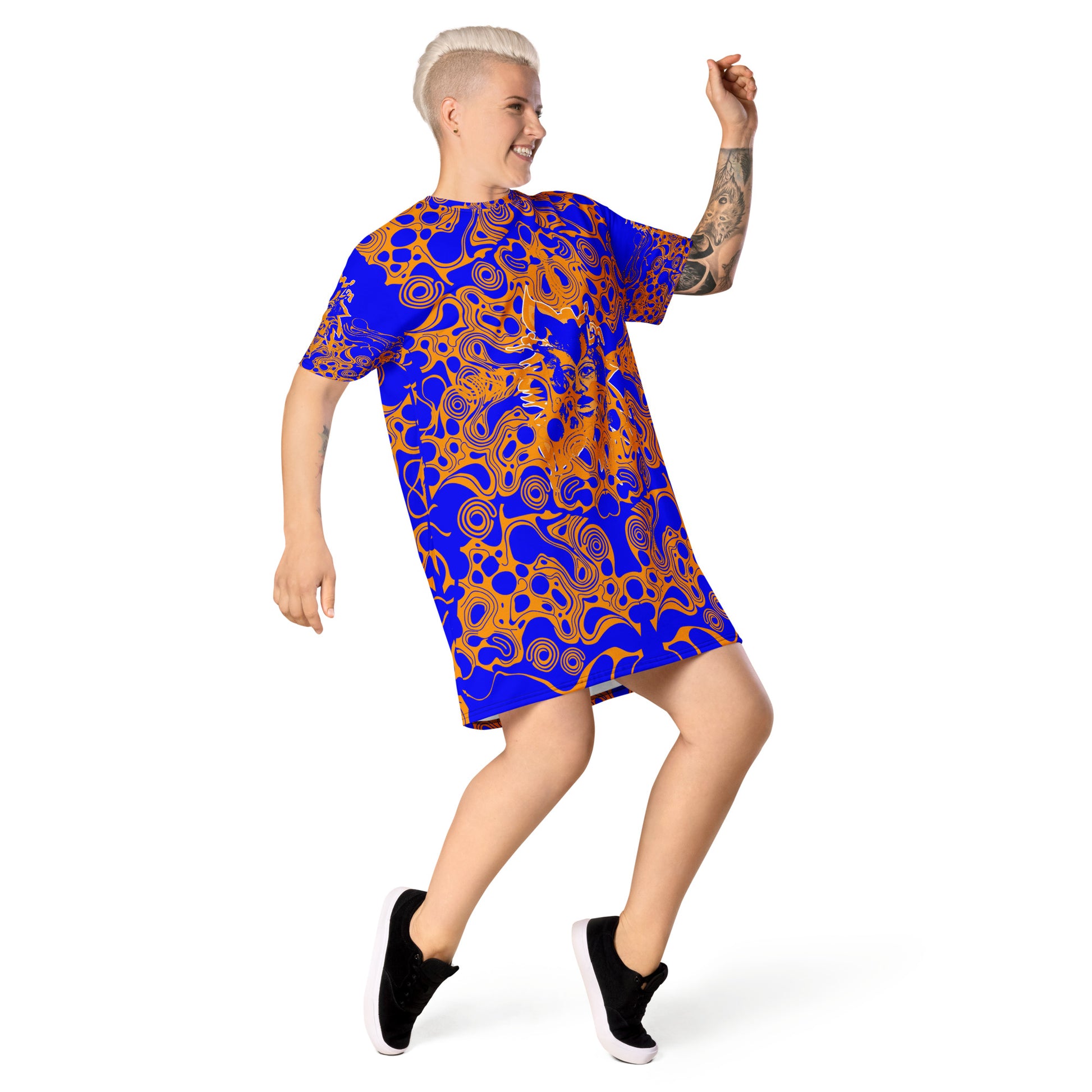 A model wearing bold blue and orange t-shirt dress from Kloe Store featuring intricate abstract patterns and a central artistic face design, offering a stylish and edgy streetwear look.
