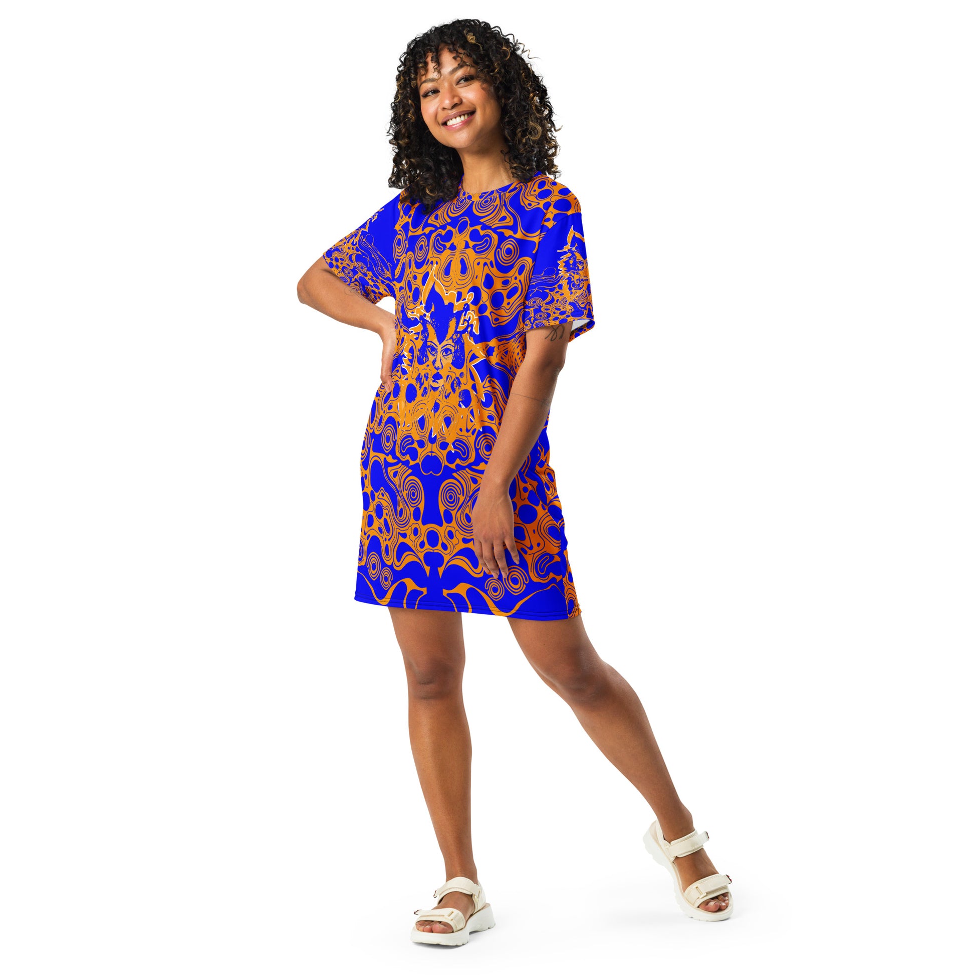 A model wearing bold blue and orange t-shirt dress from Kloe Store featuring intricate abstract patterns and a central artistic face design, offering a stylish and edgy streetwear look.