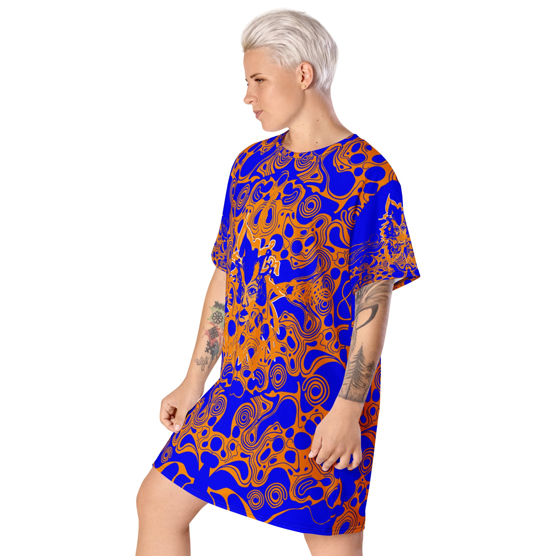 A model wearing bold blue and orange t-shirt dress from Kloe Store featuring intricate abstract patterns and a central artistic face design, offering a stylish and edgy streetwear look.