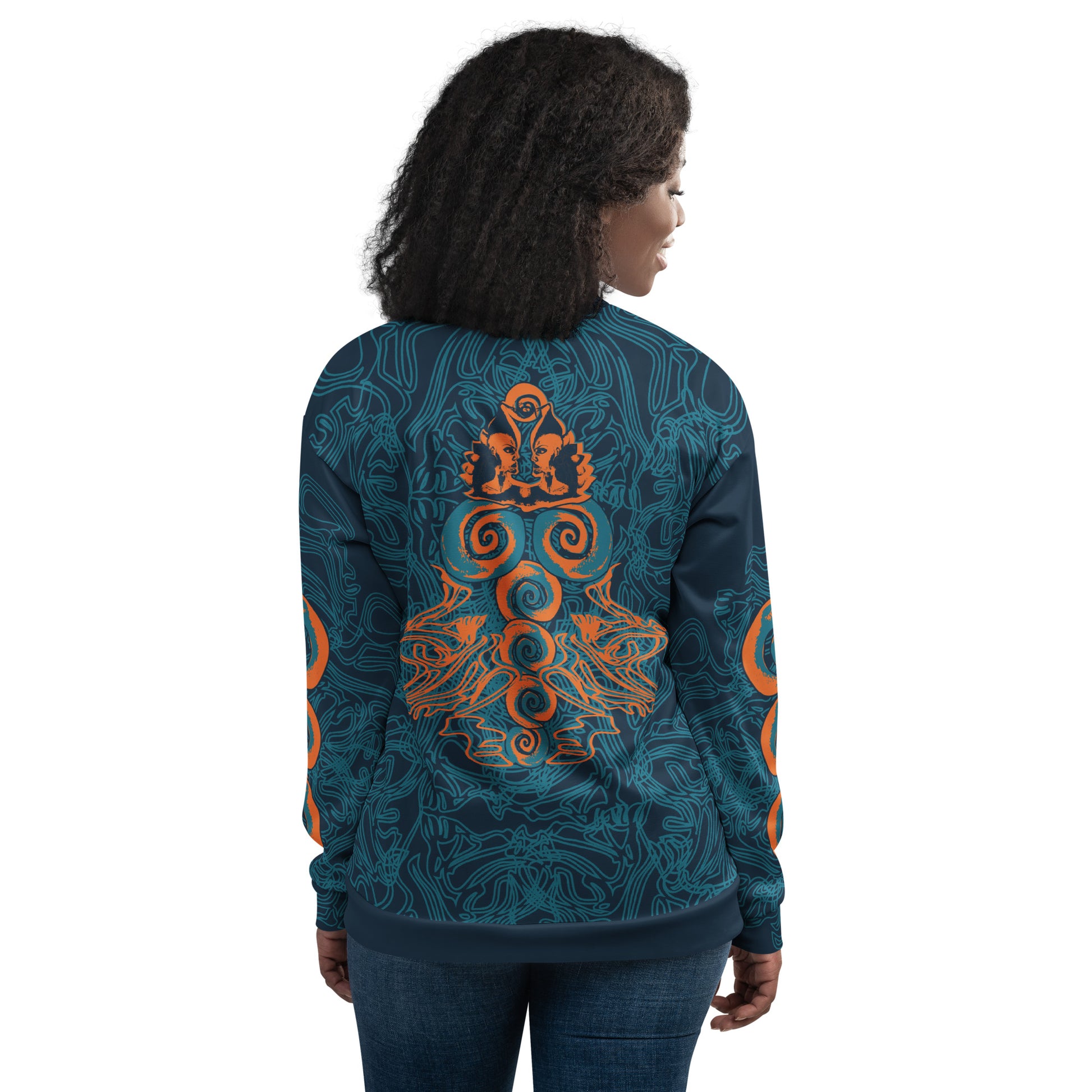 Back view of a navy blue bomber jacket featuring intricate cyan linework and bold orange mirrored face motifs, with swirling tribal-inspired patterns, on a model.