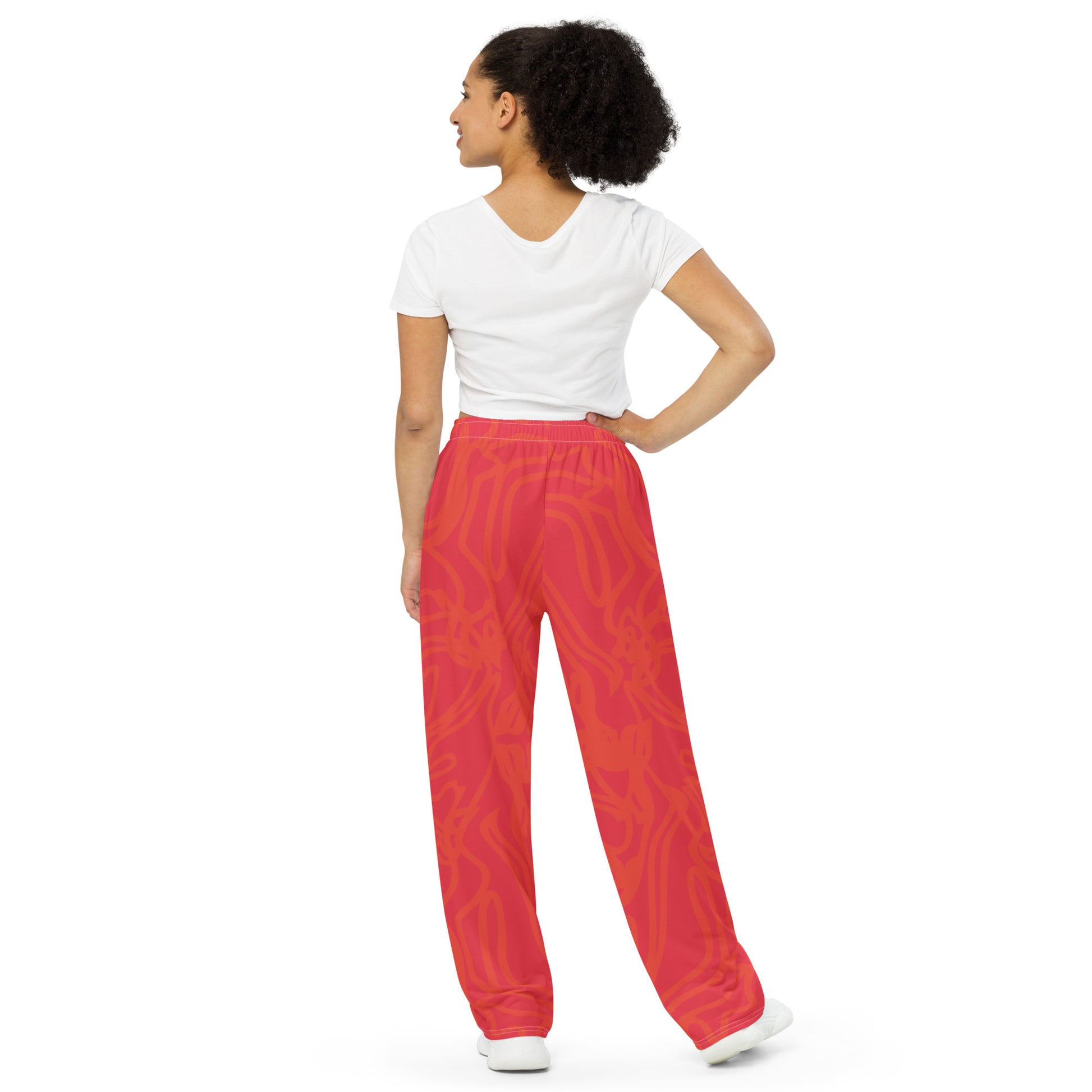 Wide-leg pants with a red base and abstract brushstroke side panels in yellow, green, and black, inspired by bold color play and cultural expression.