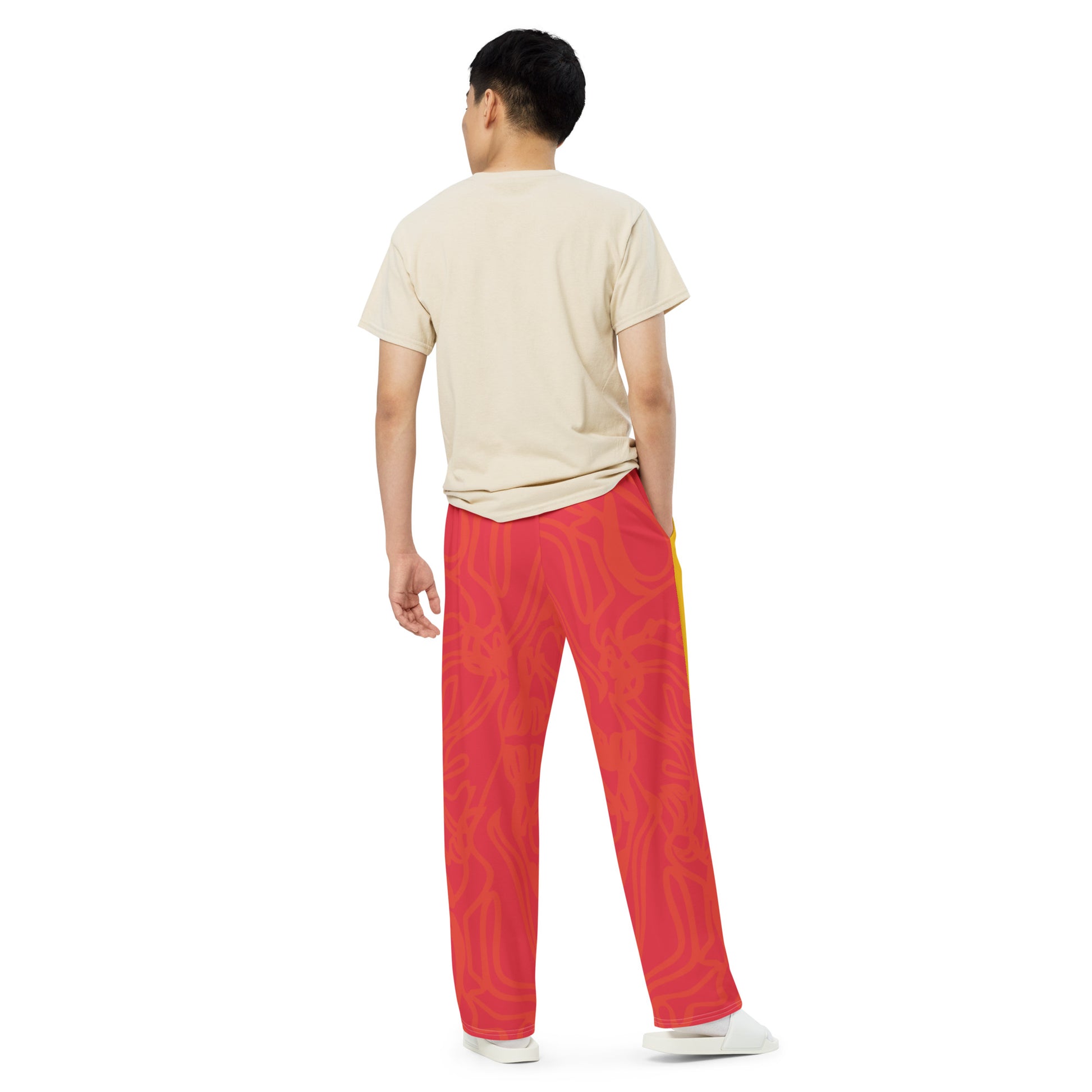 Wide-leg pants with a red base and abstract brushstroke side panels in yellow, green, and black, inspired by bold color play and cultural expression.