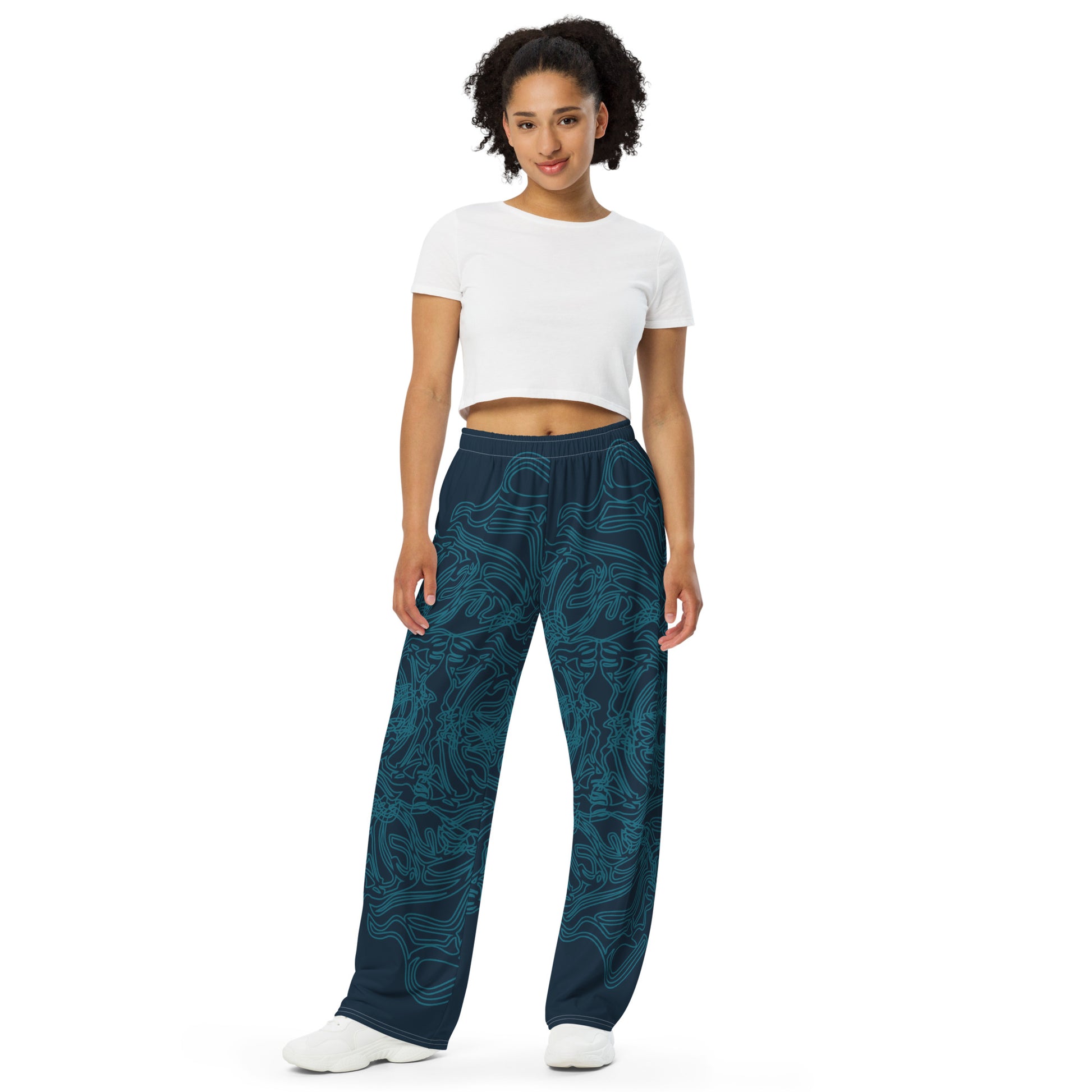 Navy blue wide-leg pants featuring intricate cyan linework, creating a fluid and artistic pattern for a bold statement look, on a model.