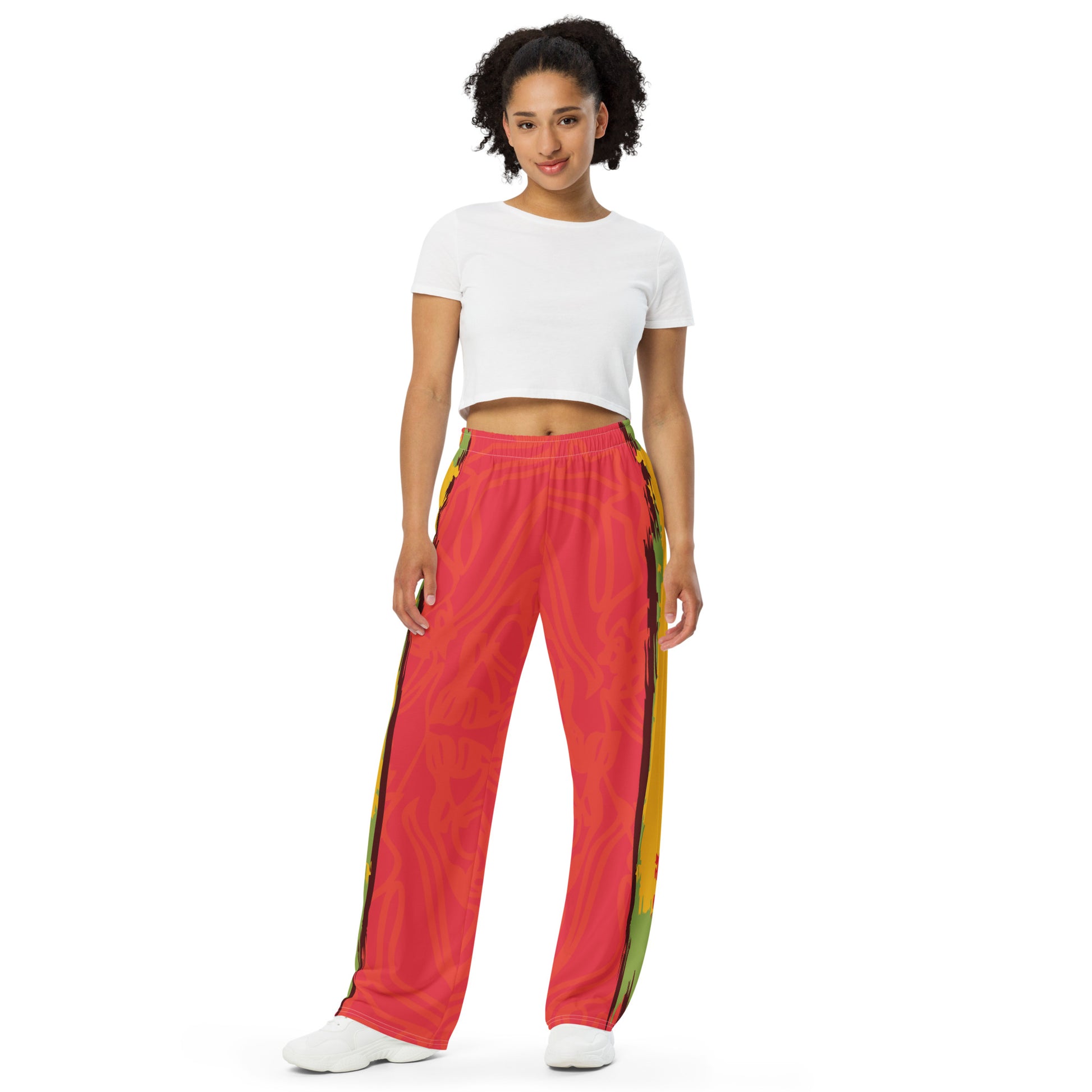 Wide-leg pants with a red base and abstract brushstroke side panels in yellow, green, and black, inspired by bold color play and cultural expression.