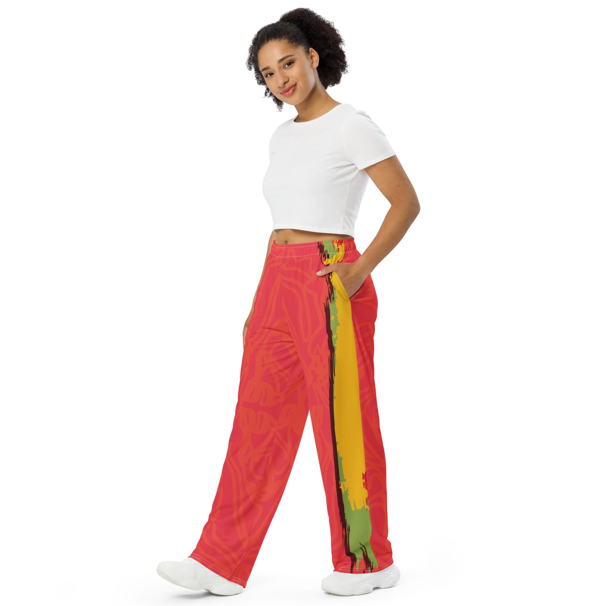 Wide-leg pants with a red base and abstract brushstroke side panels in yellow, green, and black, inspired by bold color play and cultural expression.