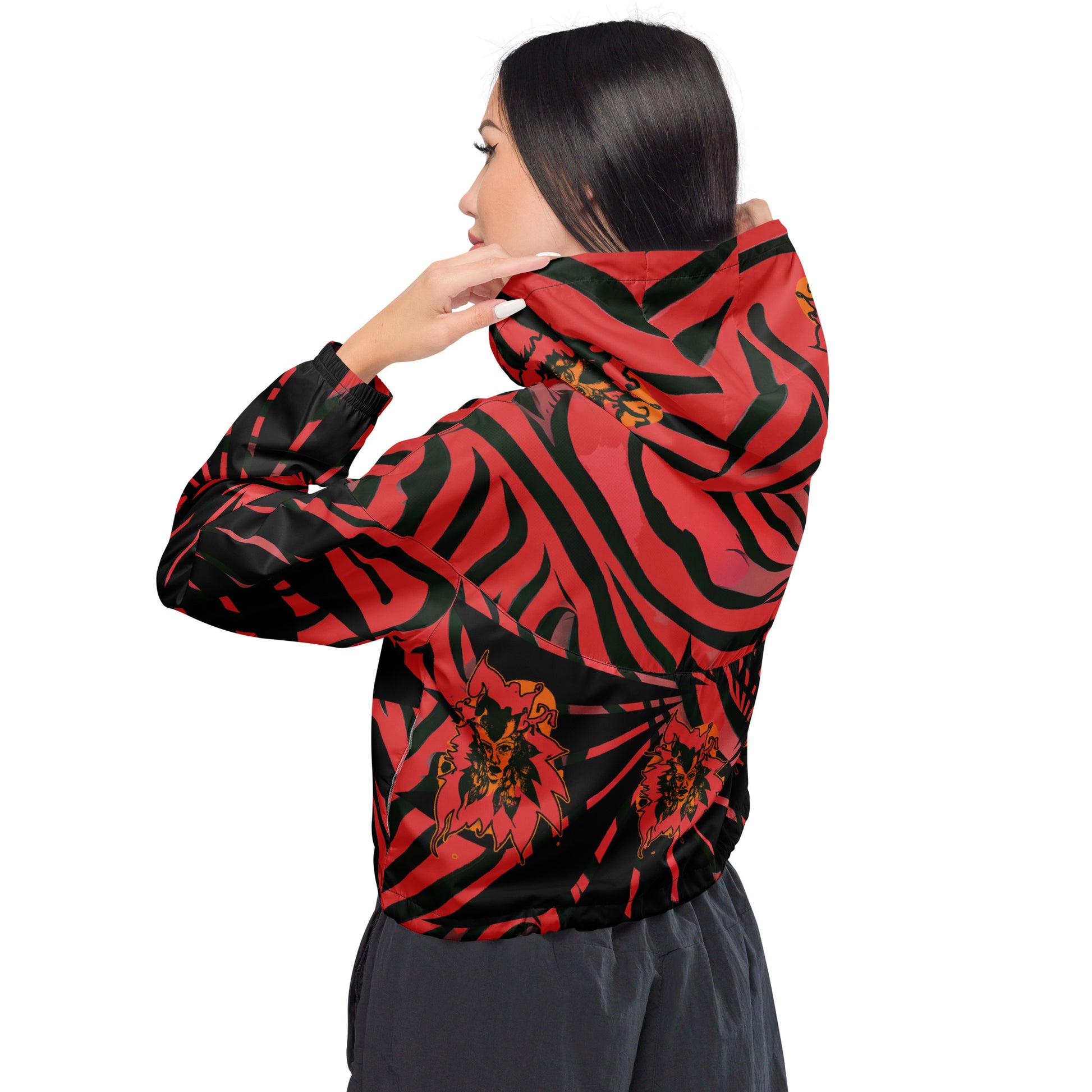 The model wearing red and black cropped women's windbreaker from Kloe Store featuring a bold swirling pattern, adjustable drawstring hem, and hood, showcasing trendy and stylish outerwear for modern street fashion, back view.