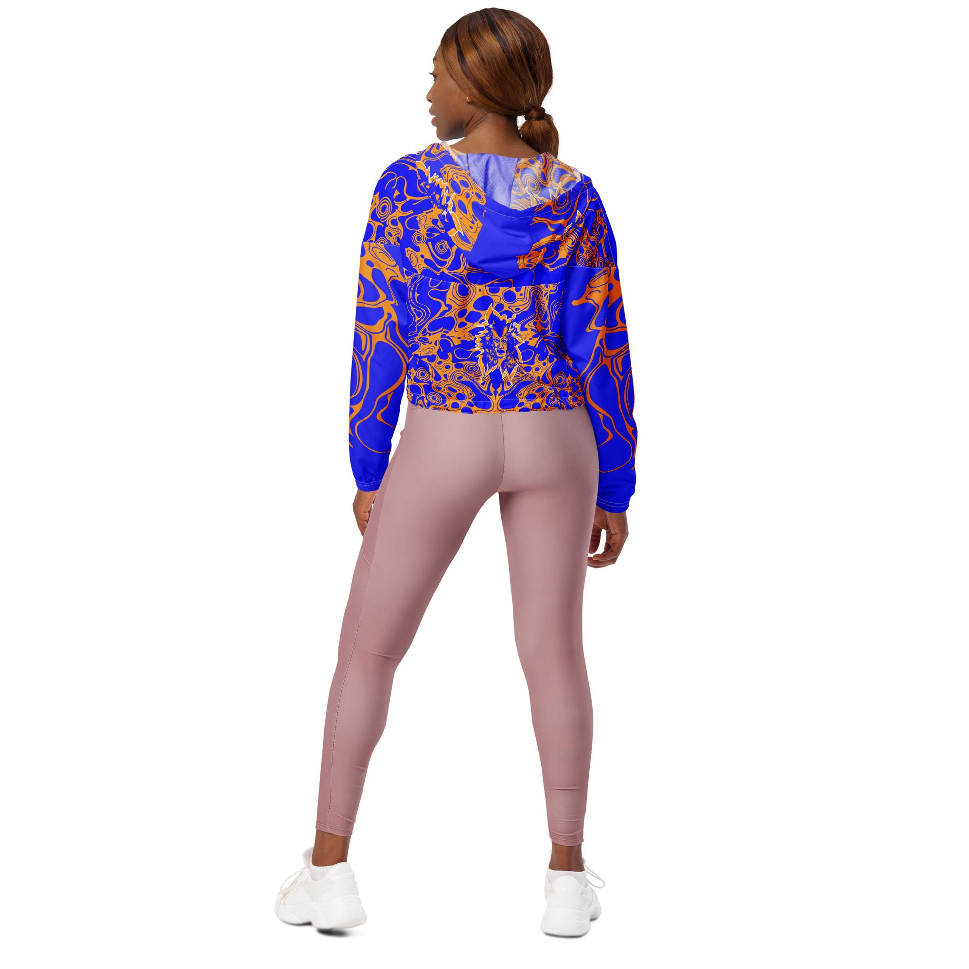 Product mockup - model wearing a vibrant blue and orange cropped windbreaker from Kloe Store featuring abstract swirl pattern, a front zipper, drawstring hood, and elastic cuffs, offering a stylish and modern streetwear look.