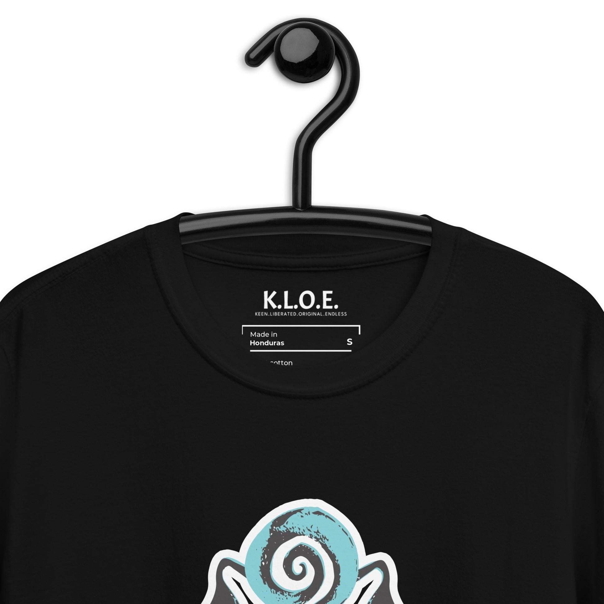 A model wearing black K.L.O.E. t-shirt showcasing a hand-drawn design of two mirrored faces in black and teal, embodying culturally inspired, bohemian style fashion focused on individuality and artistic expression, detail view, showing the inside label.