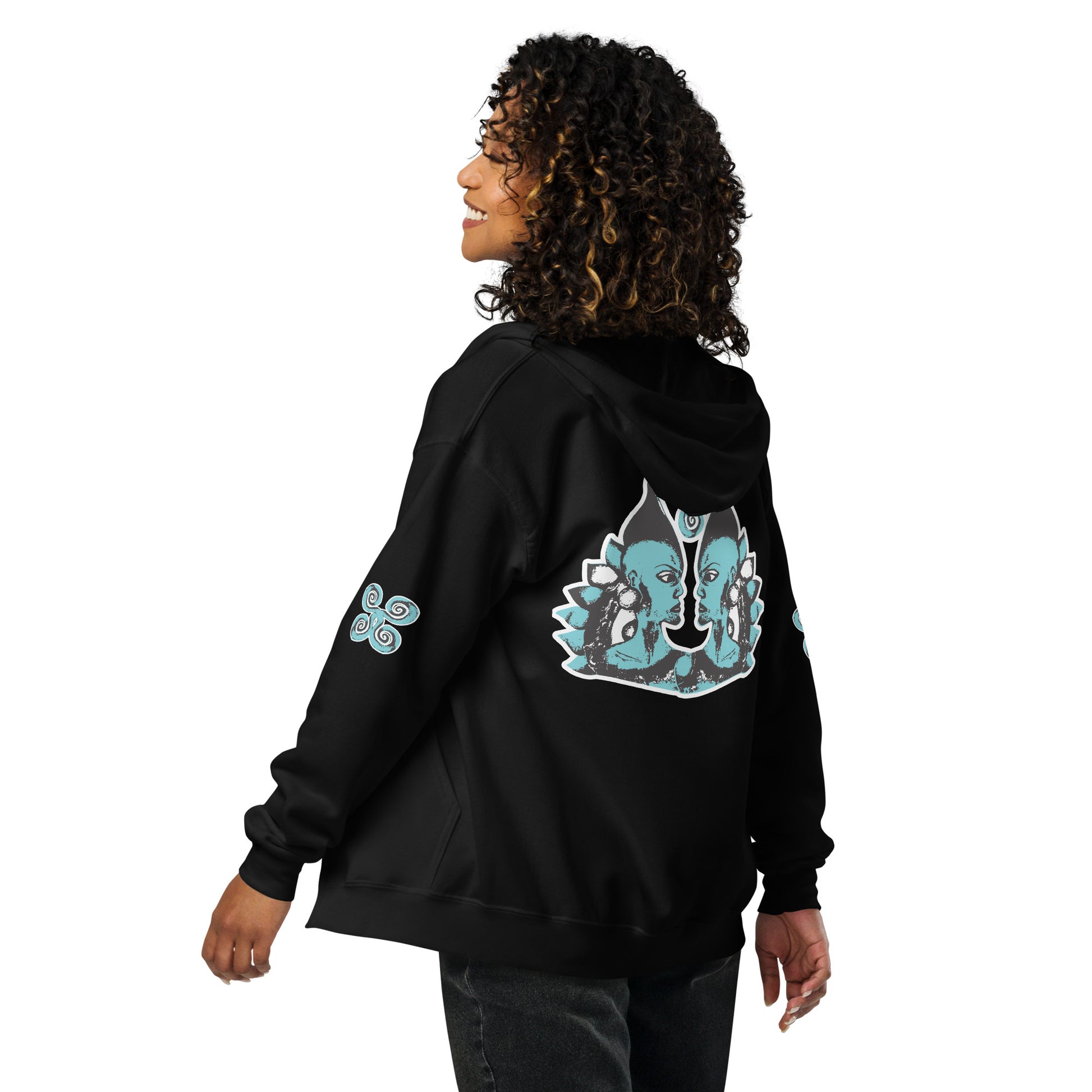 The model wearing black zip-up hoodie featuring a striking, hand-drawn graphic on the back of two mirrored female figures with intricate headpieces in black and teal, connected by a central spiral element, on the back. Teal spiral accents appear on each sleeve, adding a touch of cultural artistry. This K.L.O.E. design embodies modern boho style and expressive, artisan-crafted fashion, ideal for those who embrace unique, eco-friendly apparel and global inspiration.