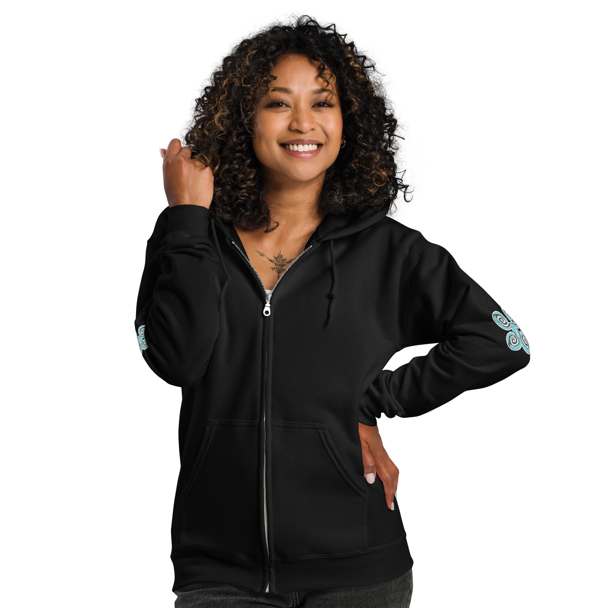 The model wearing black zip-up hoodie featuring a striking, hand-drawn graphic on the back of two mirrored female figures with intricate headpieces in black and teal, connected by a central spiral element, on the back. Teal spiral accents appear on each sleeve, adding a touch of cultural artistry. This K.L.O.E. design embodies modern boho style and expressive, artisan-crafted fashion, ideal for those who embrace unique, eco-friendly apparel and global inspiration.