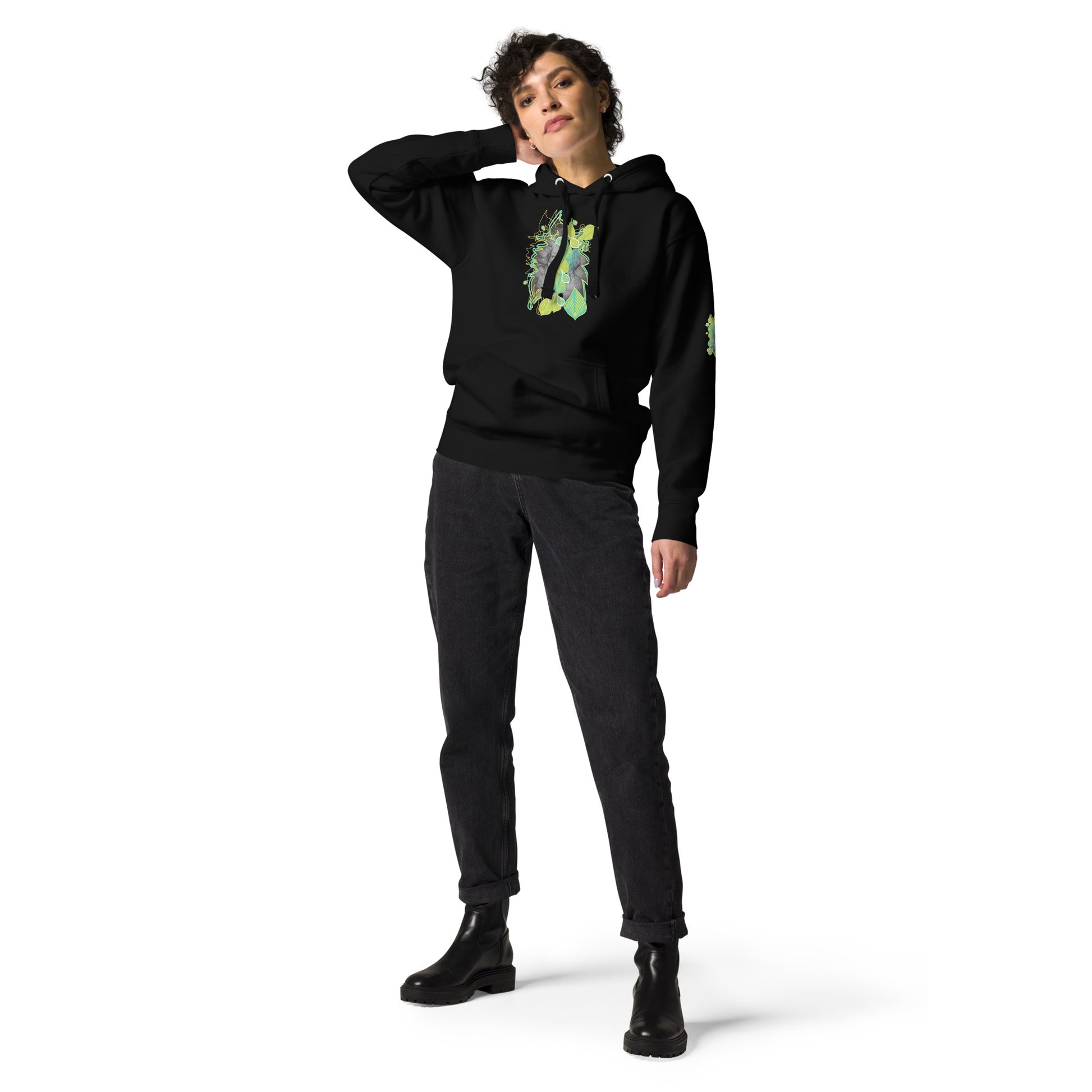 Front view of black K.L.O.E. hoodie with vibrant green and yellow leaf patterns framing a detailed hand-drawn face design. A modern bohemian style statement that celebrates individuality, artistic expression, and culturally inspired fashion, on a model.