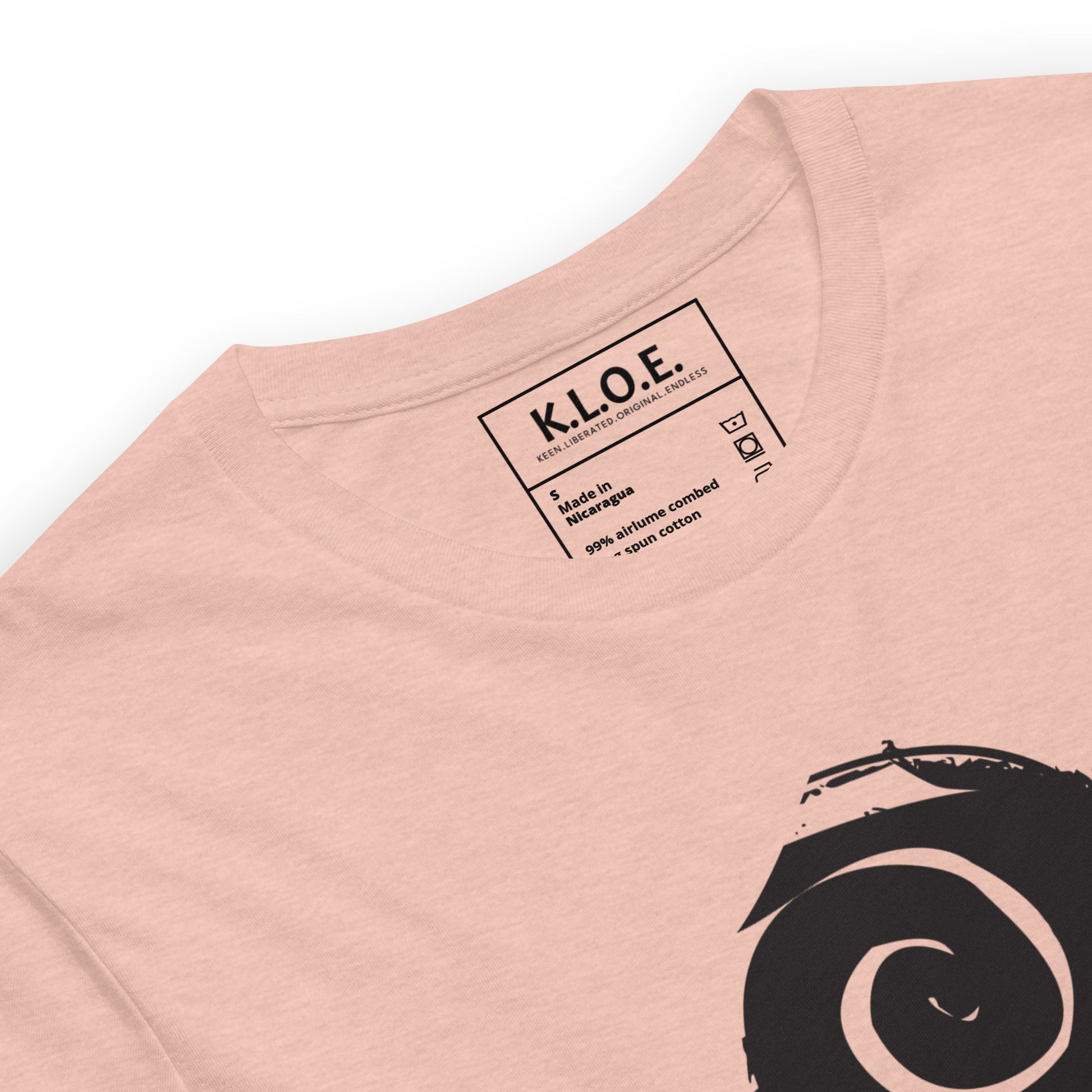 A couple wearing peach color t-shirt featuring a hand-drawn black ink design of two mirrored female figures with bold, intricate headpieces, connected by a swirling central element. This artistic piece from K.L.O.E. embraces cultural inspiration and self-expression, crafted for those who appreciate unique, expressive fashion and modern bohemian style. Detail view, showing the inside label.