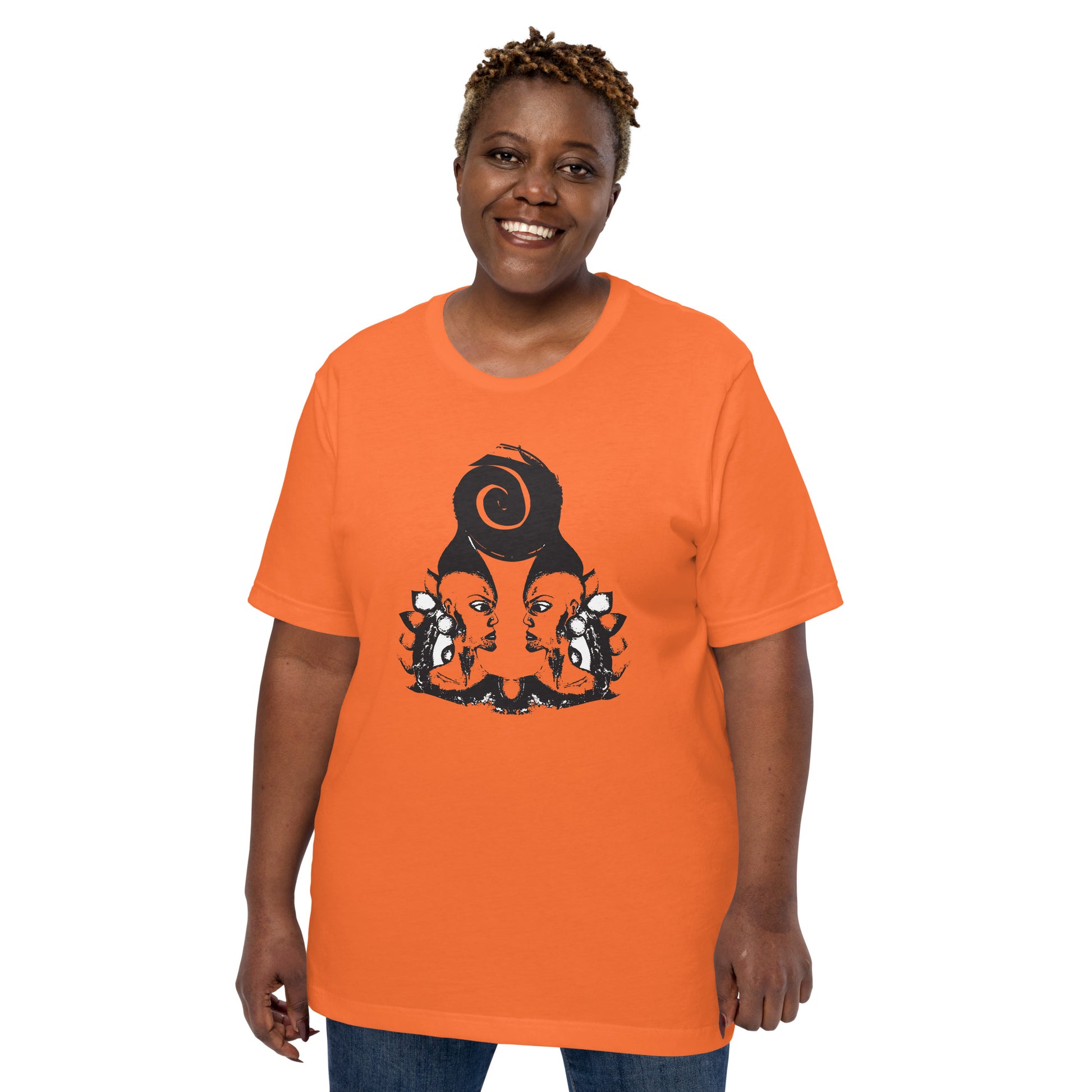 A plus size model wearing orange t-shirt featuring a hand-drawn black ink design of two mirrored female figures with bold, intricate headpieces, connected by a swirling central element. This artistic piece from K.L.O.E. embraces cultural inspiration and self-expression, crafted for those who appreciate unique, expressive fashion and modern bohemian style.