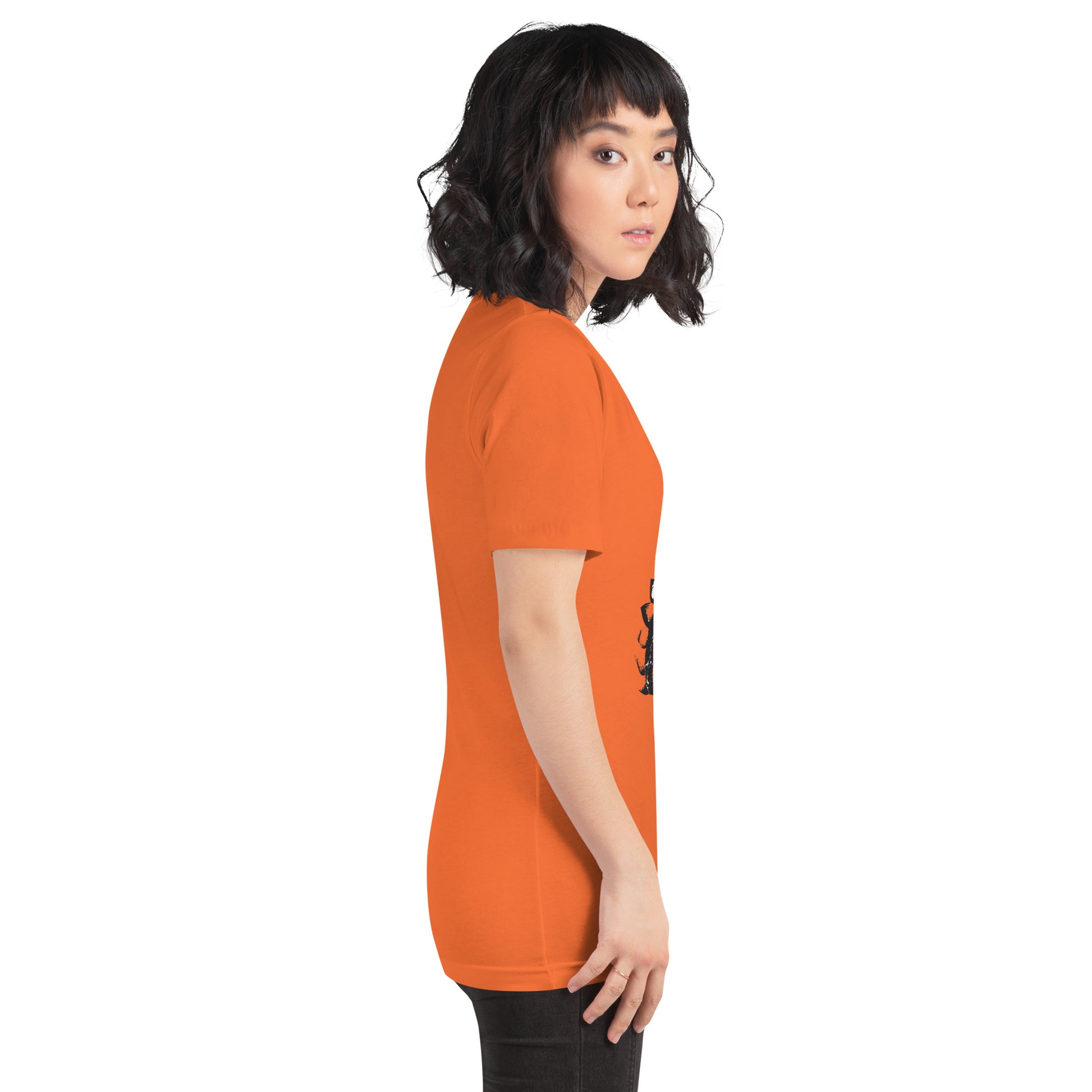 A model wearing orange t-shirt featuring a hand-drawn black ink design of two mirrored female figures with bold, intricate headpieces, connected by a swirling central element. This artistic piece from K.L.O.E. embraces cultural inspiration and self-expression, crafted for those who appreciate unique, expressive fashion and modern bohemian style, side view.