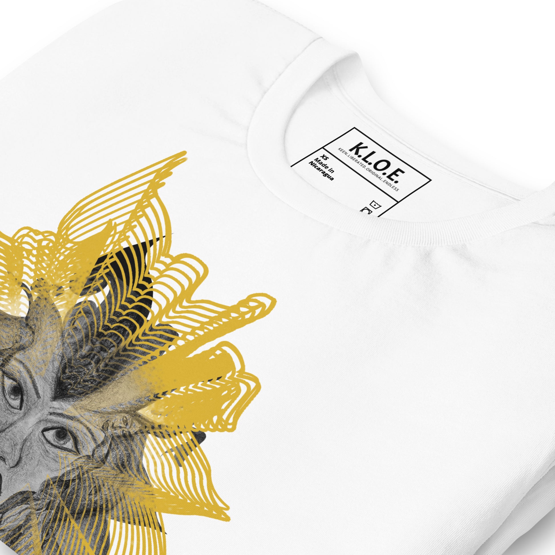 Detail view of the front side of a white K.L.O.E. T-shirt featuring a striking hand-drawn face design surrounded by radiant golden abstract patterns—an artistic and empowering piece of handcrafted fashion, blending bohemian style clothing with contemporary fashion for bold self-expression and individuality.