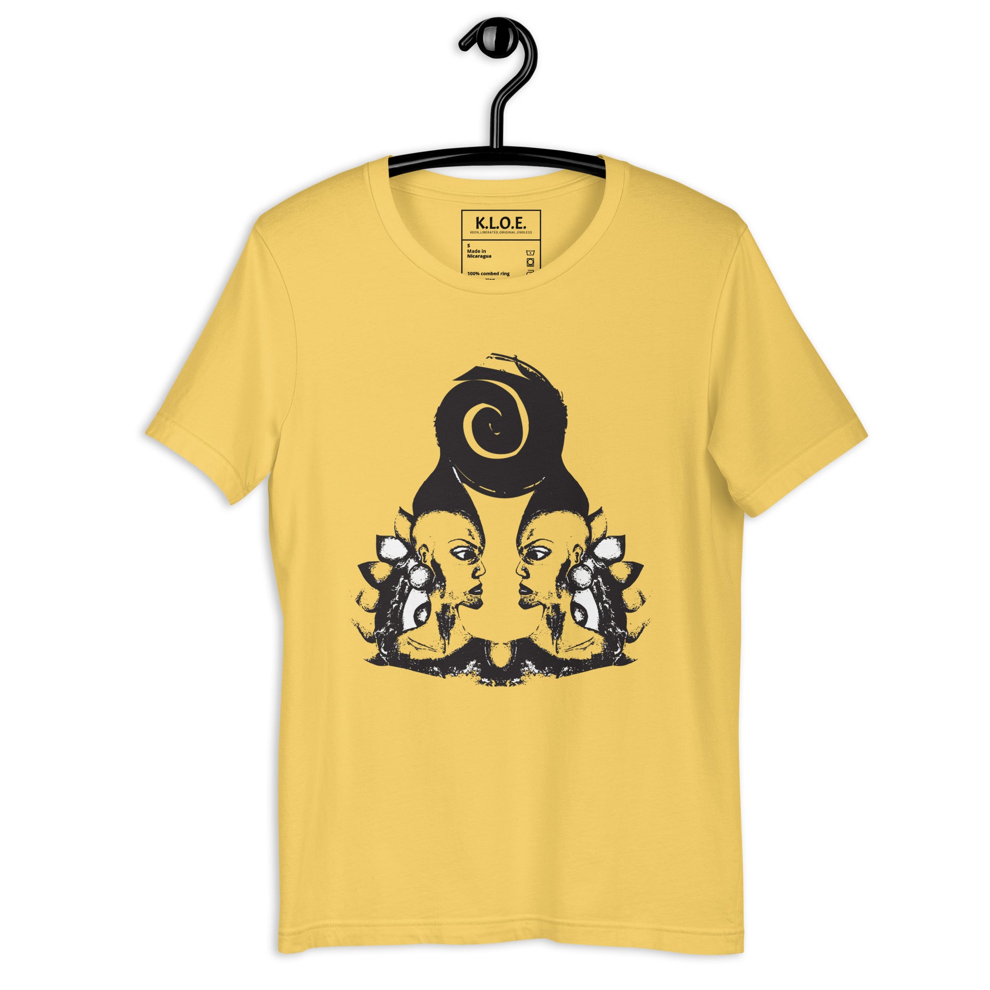 Yellow t-shirt, on a hanger, featuring wearable illustrations with an art-inspired black design of mirrored female faces and a bold central spiral symbol, celebrating expressive fashion and individuality – unique clothing by K.L.O.E.