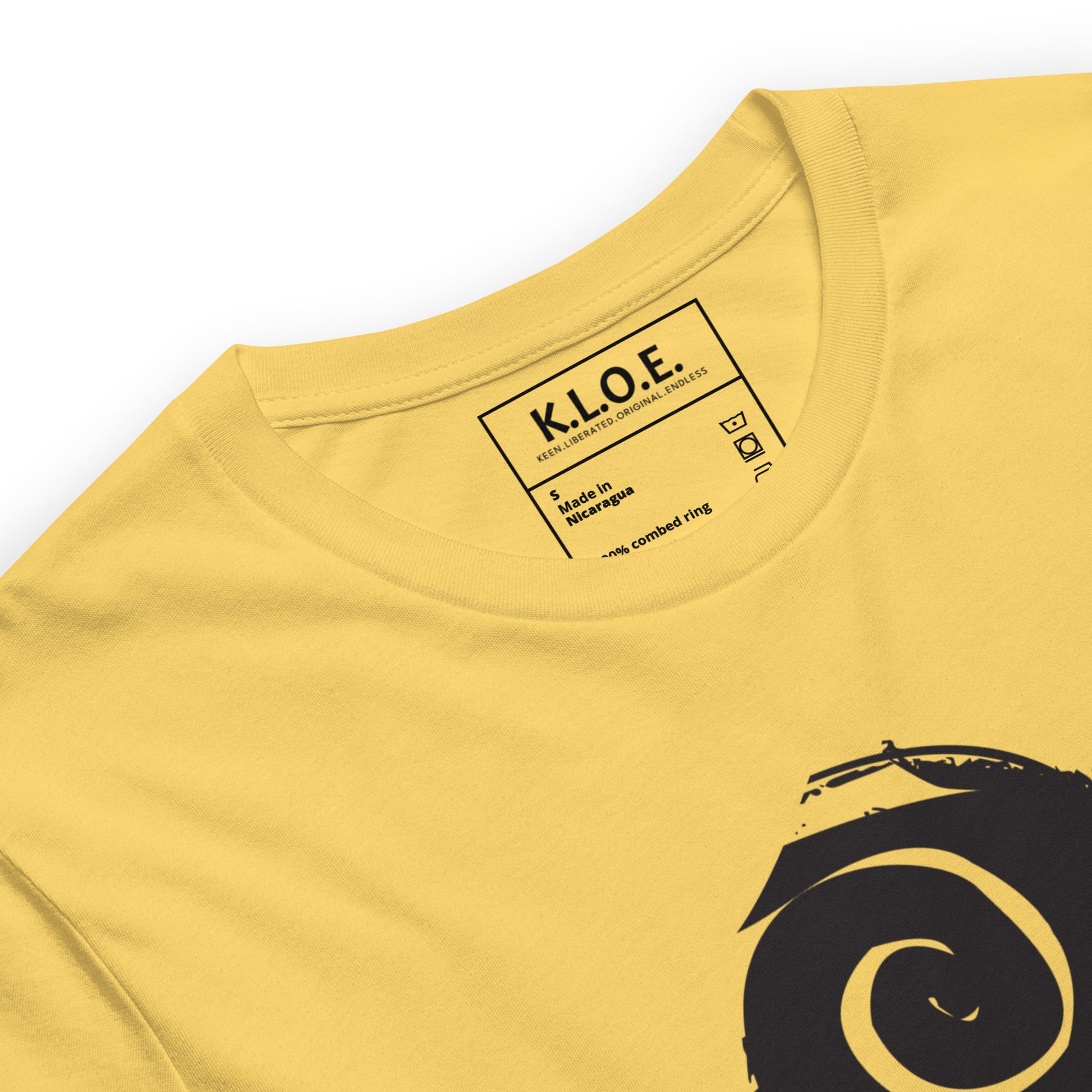 Yellow t-shirt featuring wearable illustrations with an art-inspired black design of mirrored female faces and a bold central spiral symbol, celebrating expressive fashion and individuality – unique clothing by K.L.O.E., detail view.