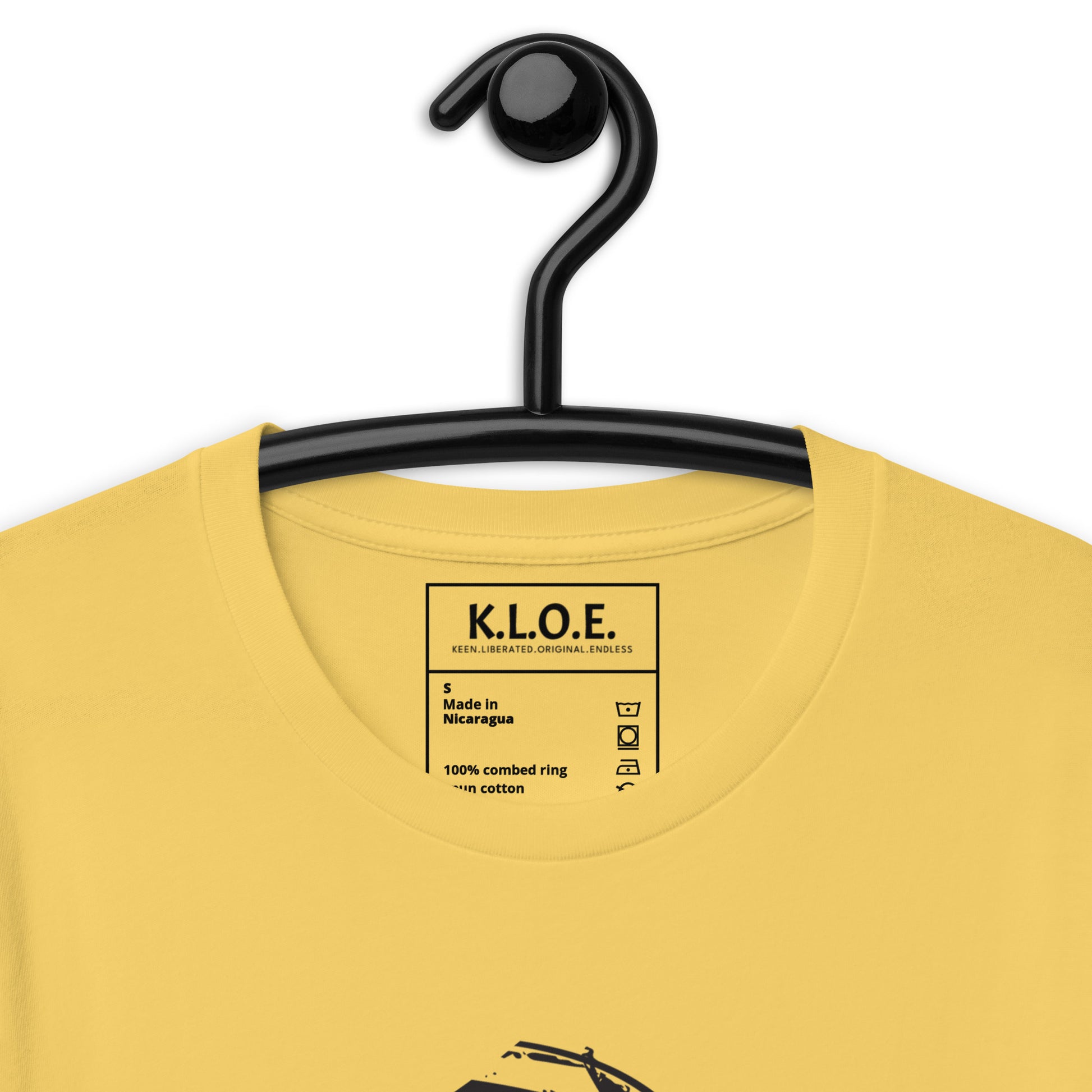 Yellow t-shirt featuring wearable illustrations with an art-inspired black design of mirrored female faces and a bold central spiral symbol, celebrating expressive fashion and individuality – unique clothing by K.L.O.E., detail view.
